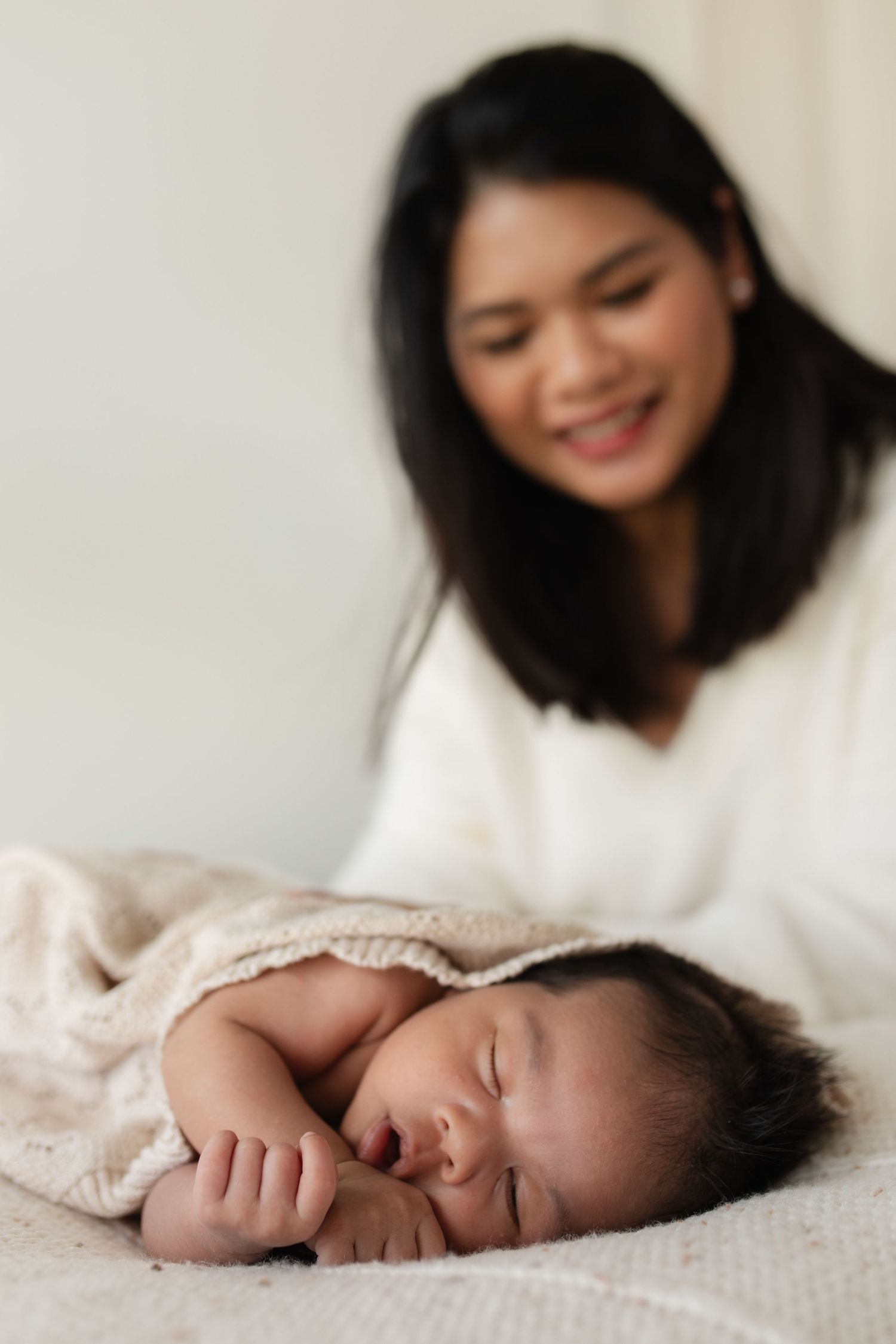 A peaceful scene of a parent watching over their sleeping infant on white bedding.