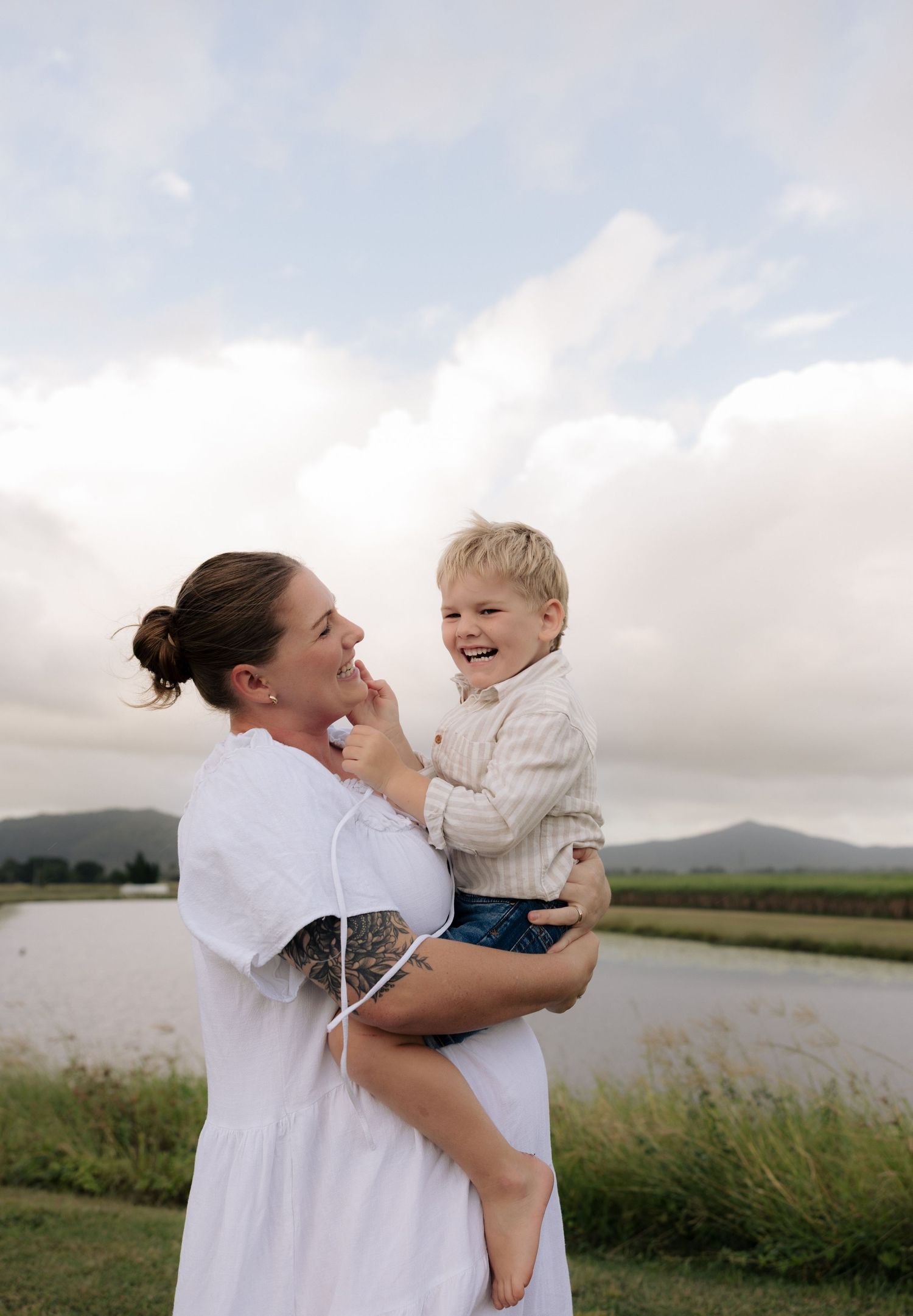 A joyful moment shared between parent and child against a cloudy lakeside backdrop.