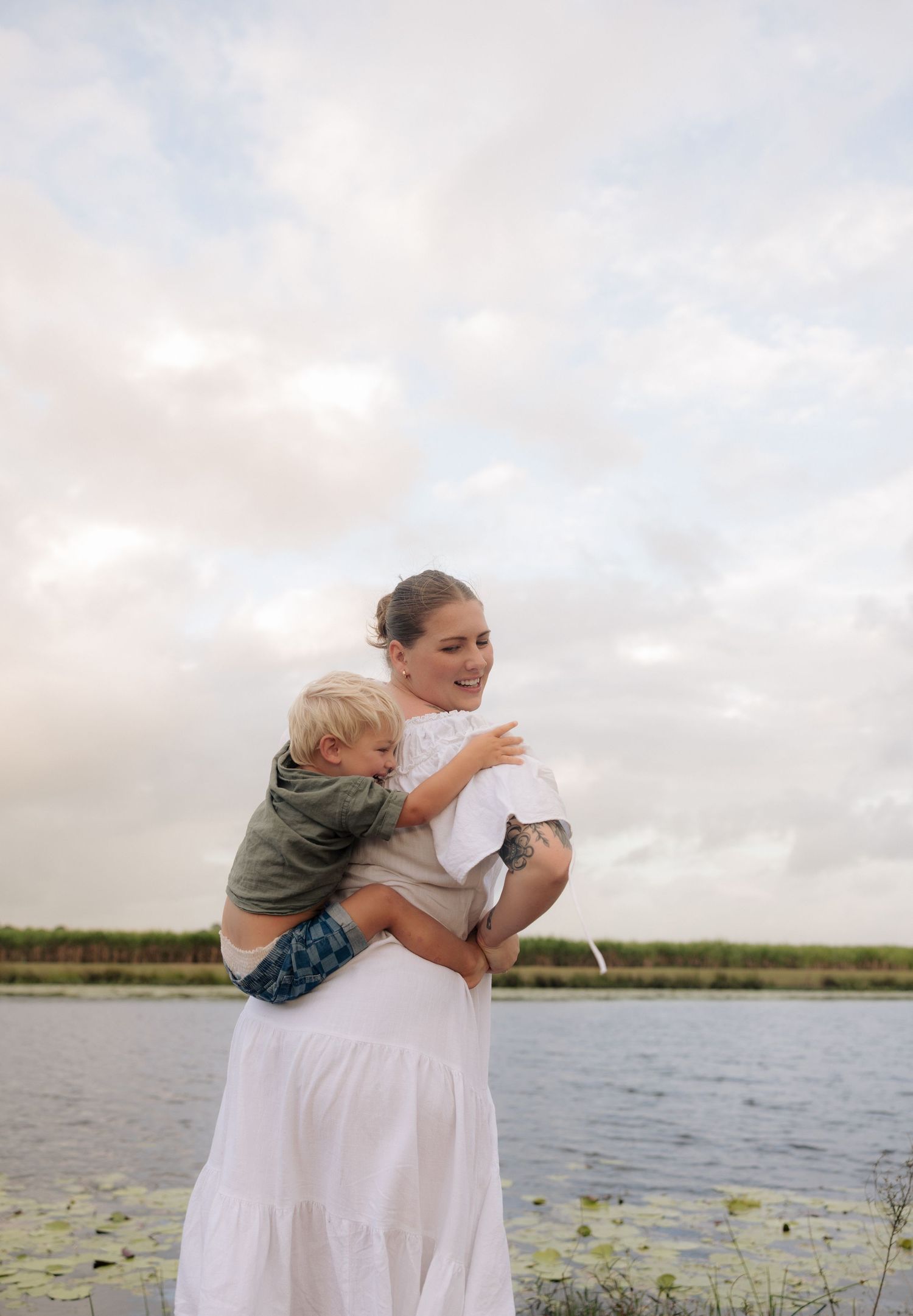 Joyful embrace between parent and child against a waterfront backdrop.