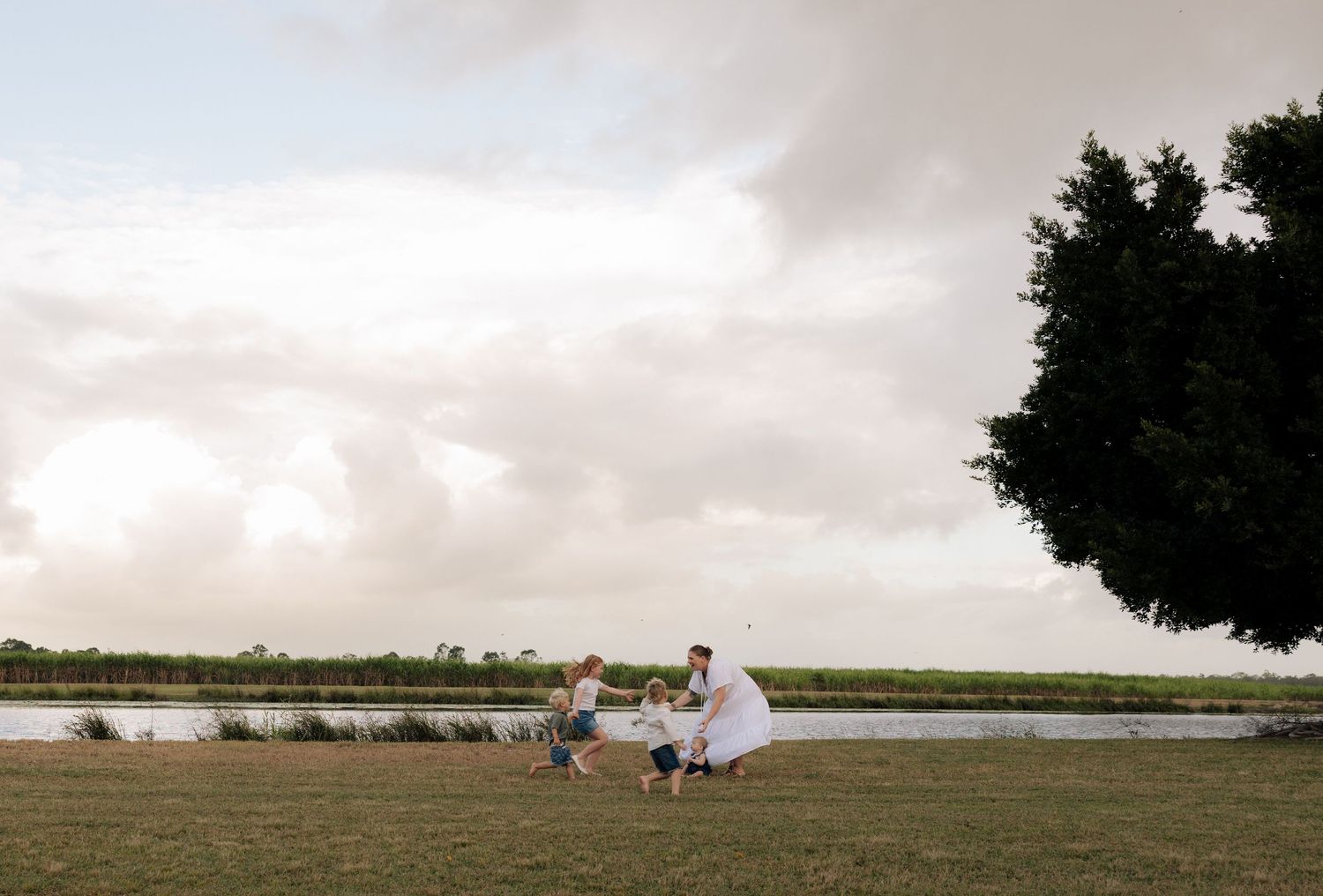 Family enjoying a sunset moment together by a serene lake with cloudy skies in the background.