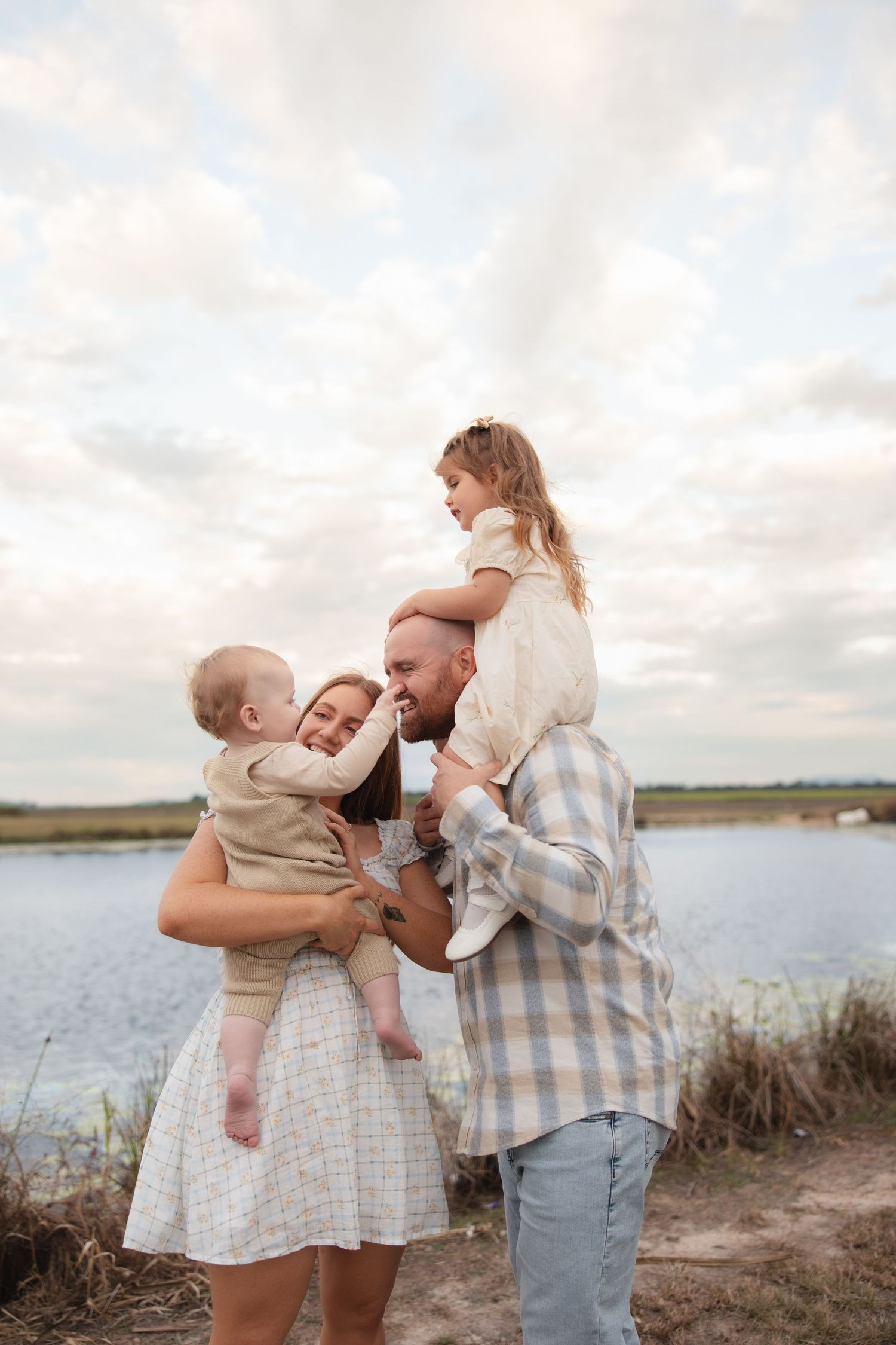 A happy family shares tender moments by a lakeside as the sun sets, creating a series of heartwarming embraces.