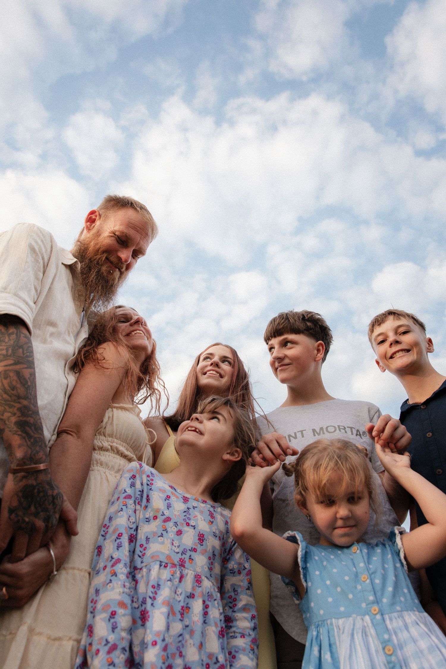 Group shares a candid moment together under a blue cloudy sky on a sunny day.