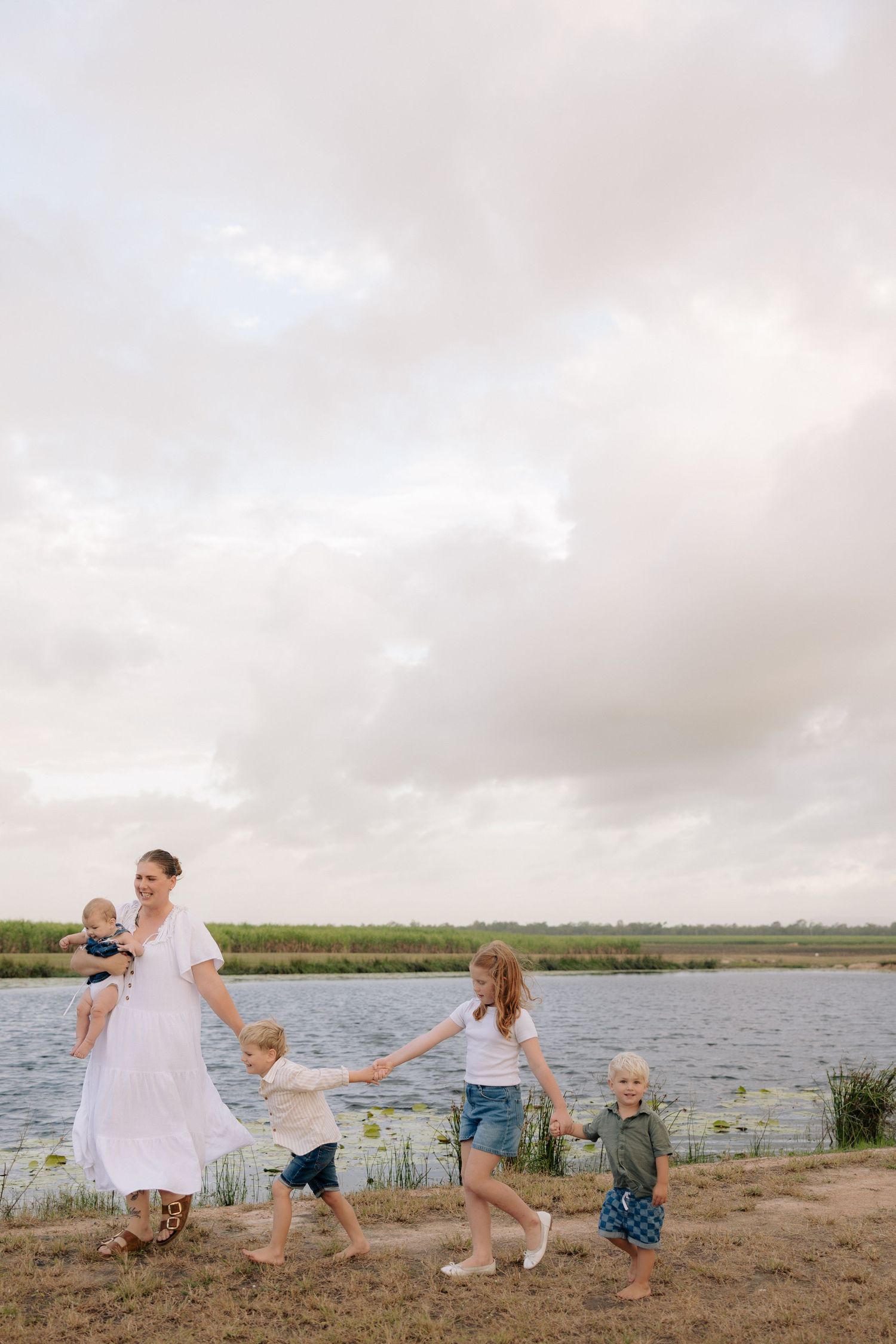 Family holding hands while walking along a scenic waterfront path.