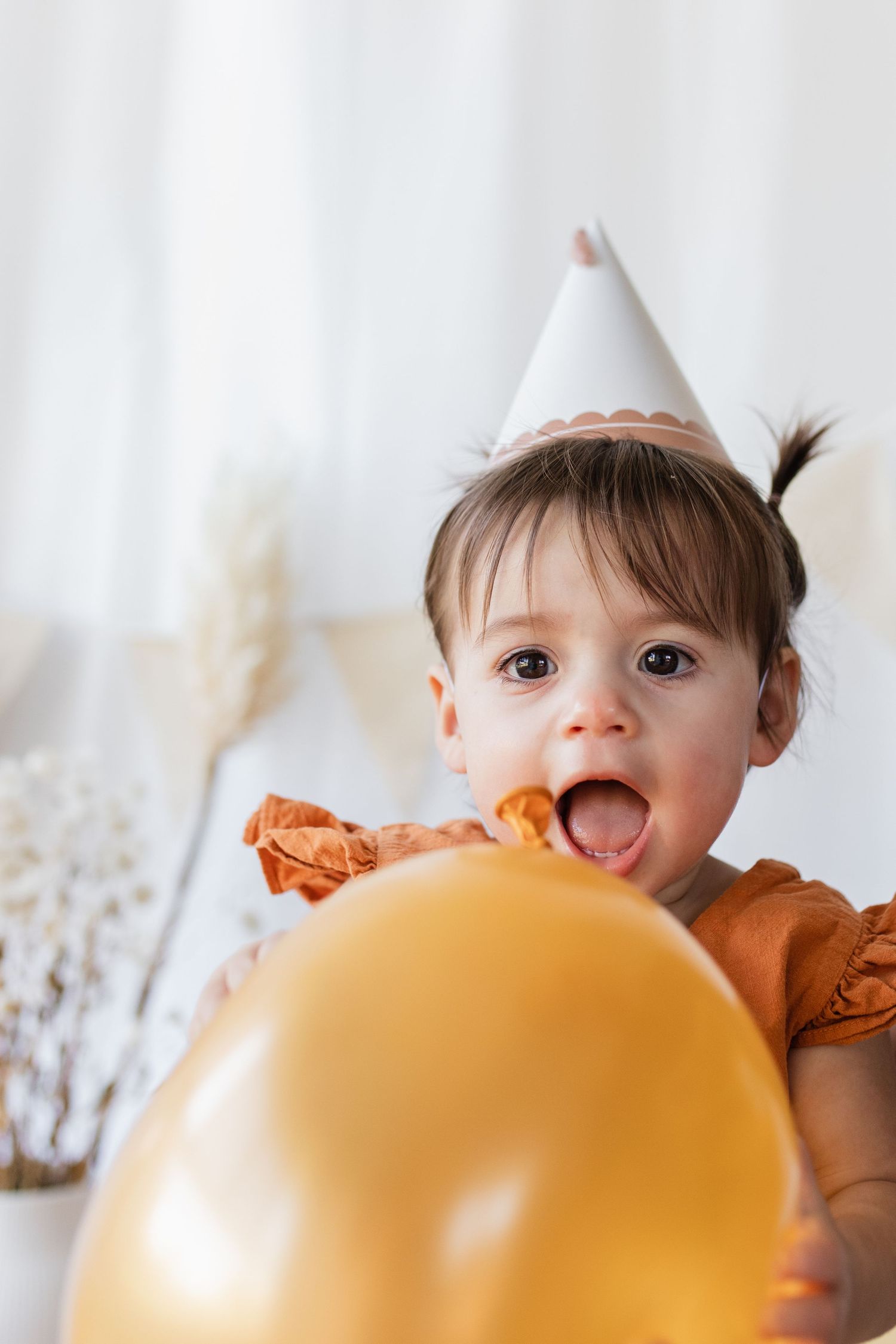 Birthday celebration with gold balloon and party hat against white backdrop.