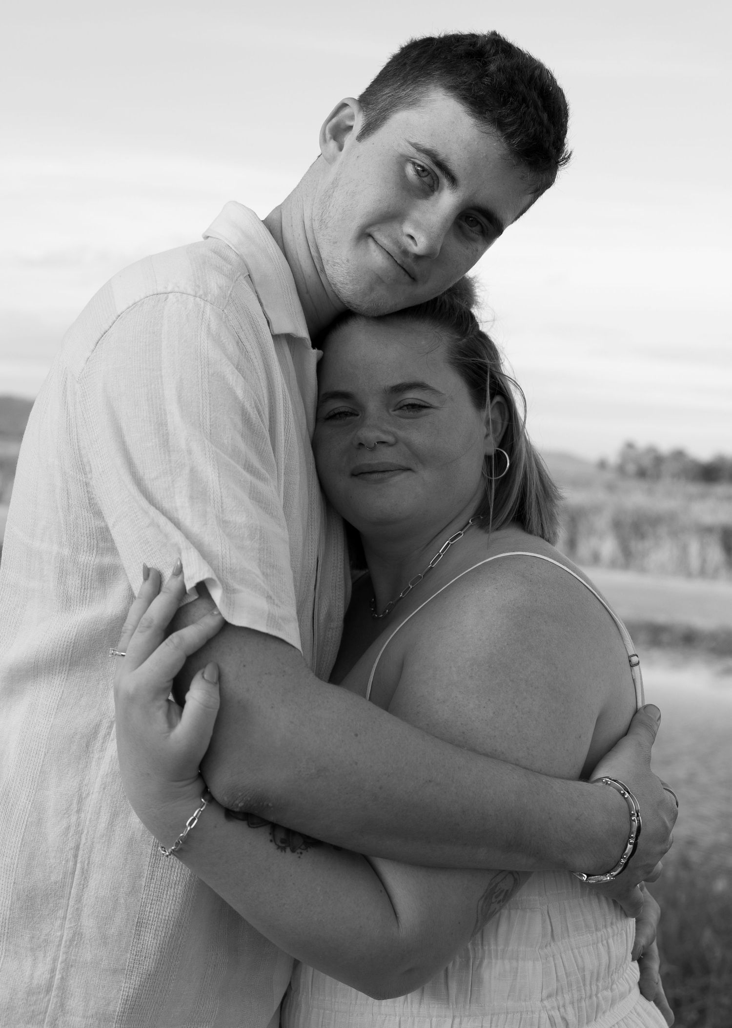 A couple embraces and poses for a romantic black and white portrait in an outdoor setting.