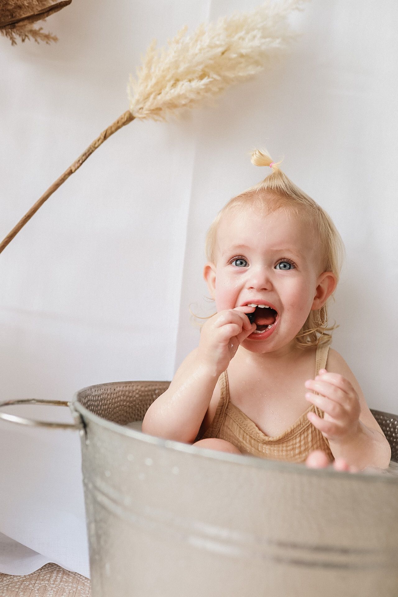 Playful moment captured in rustic metal tub with pampas grass decoration.