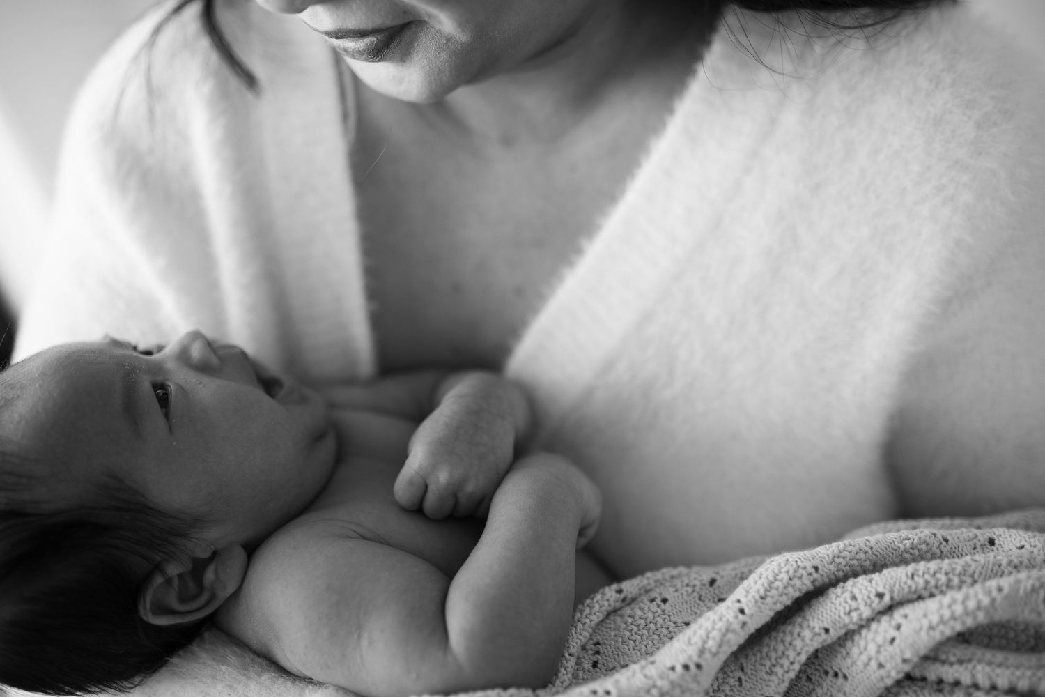 Intimate black and white portrait of nursing moment between mother and infant.