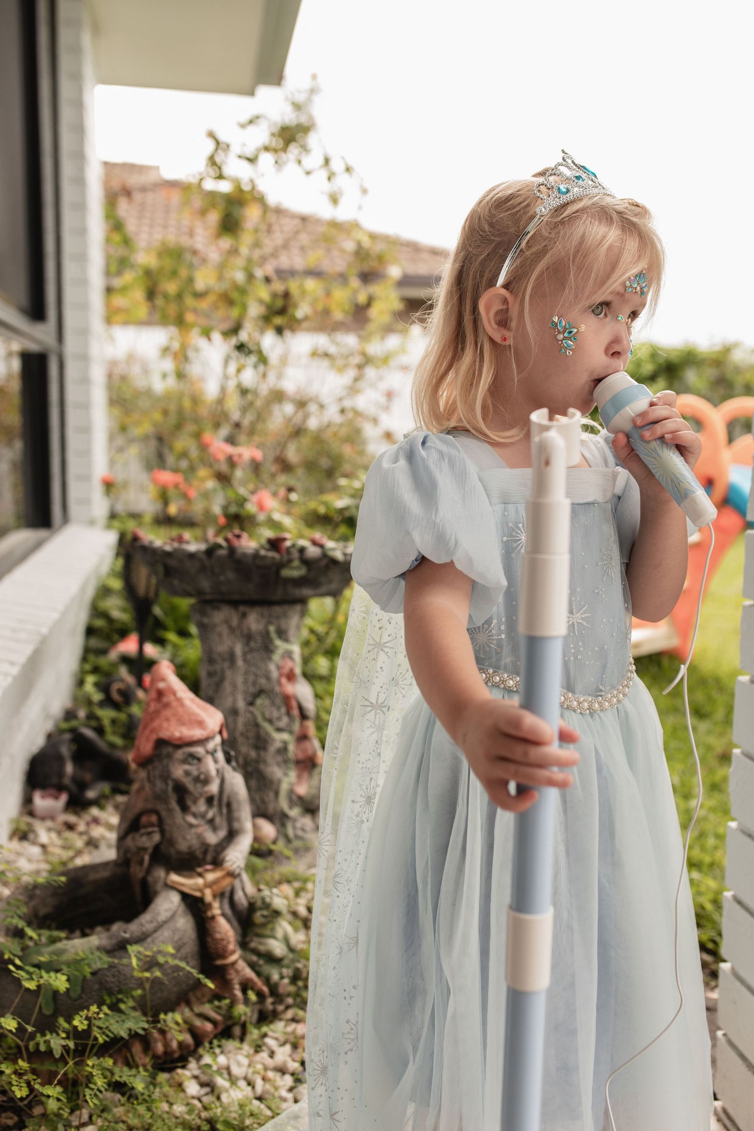 Whimsical garden setting with fairy tale dress and garden gnome decorations.