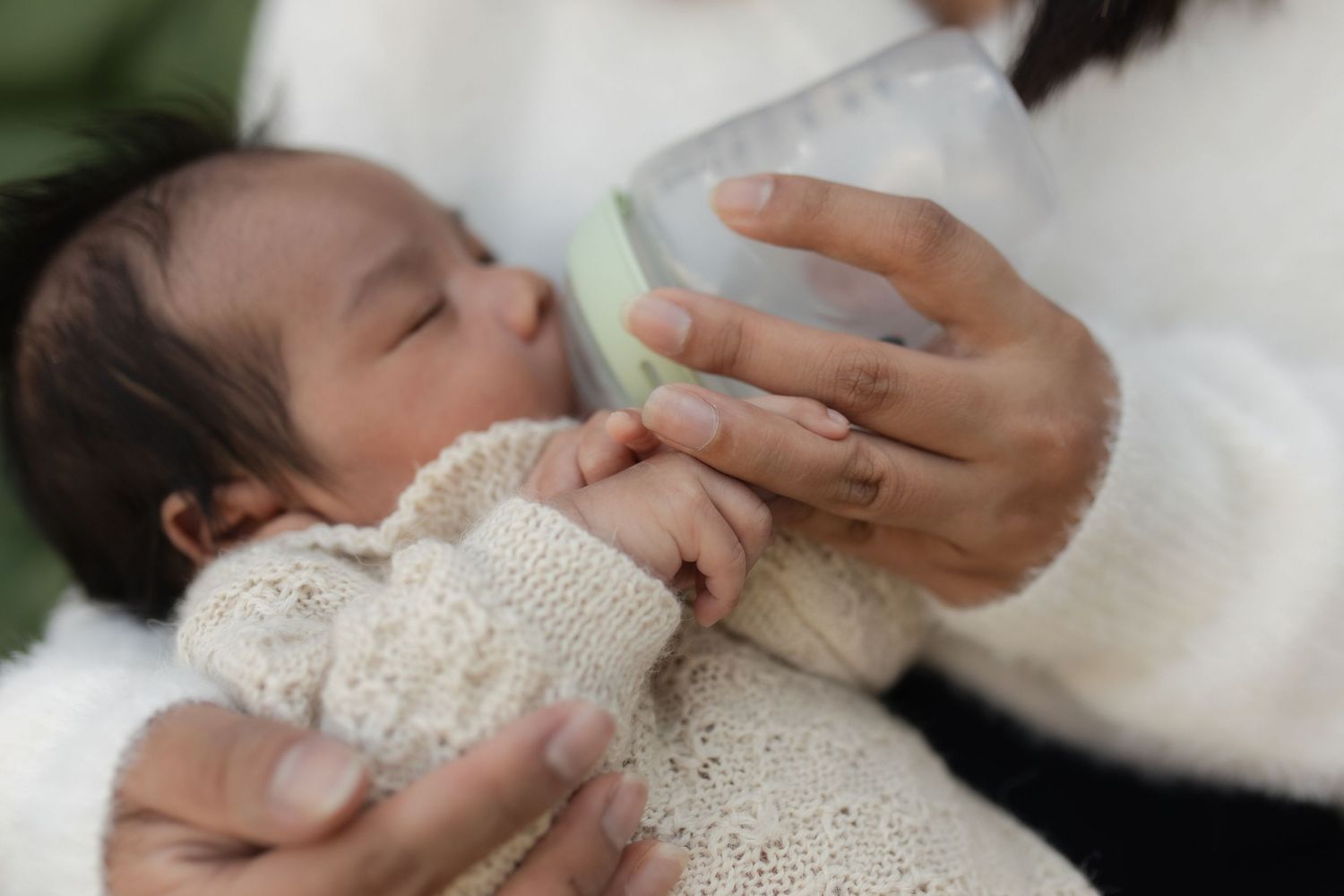 Gentle feeding time with newborn baby dressed in delicate white lace.
