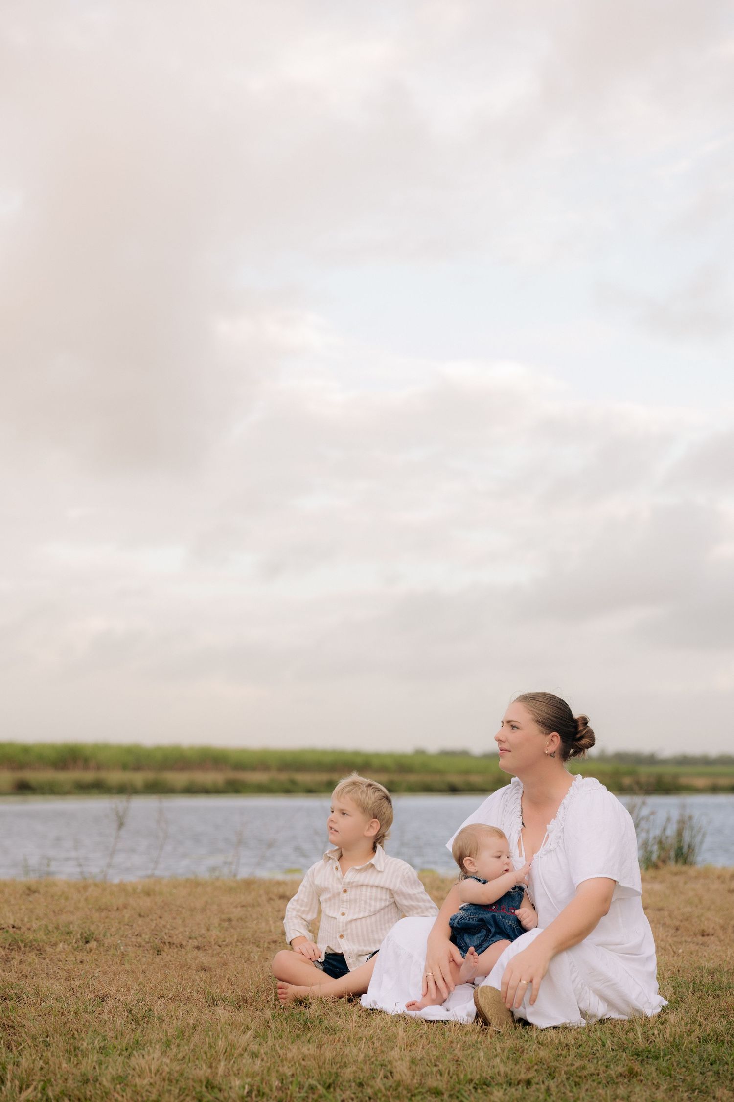 A peaceful family gathering on grassy shores of a lake under overcast skies.