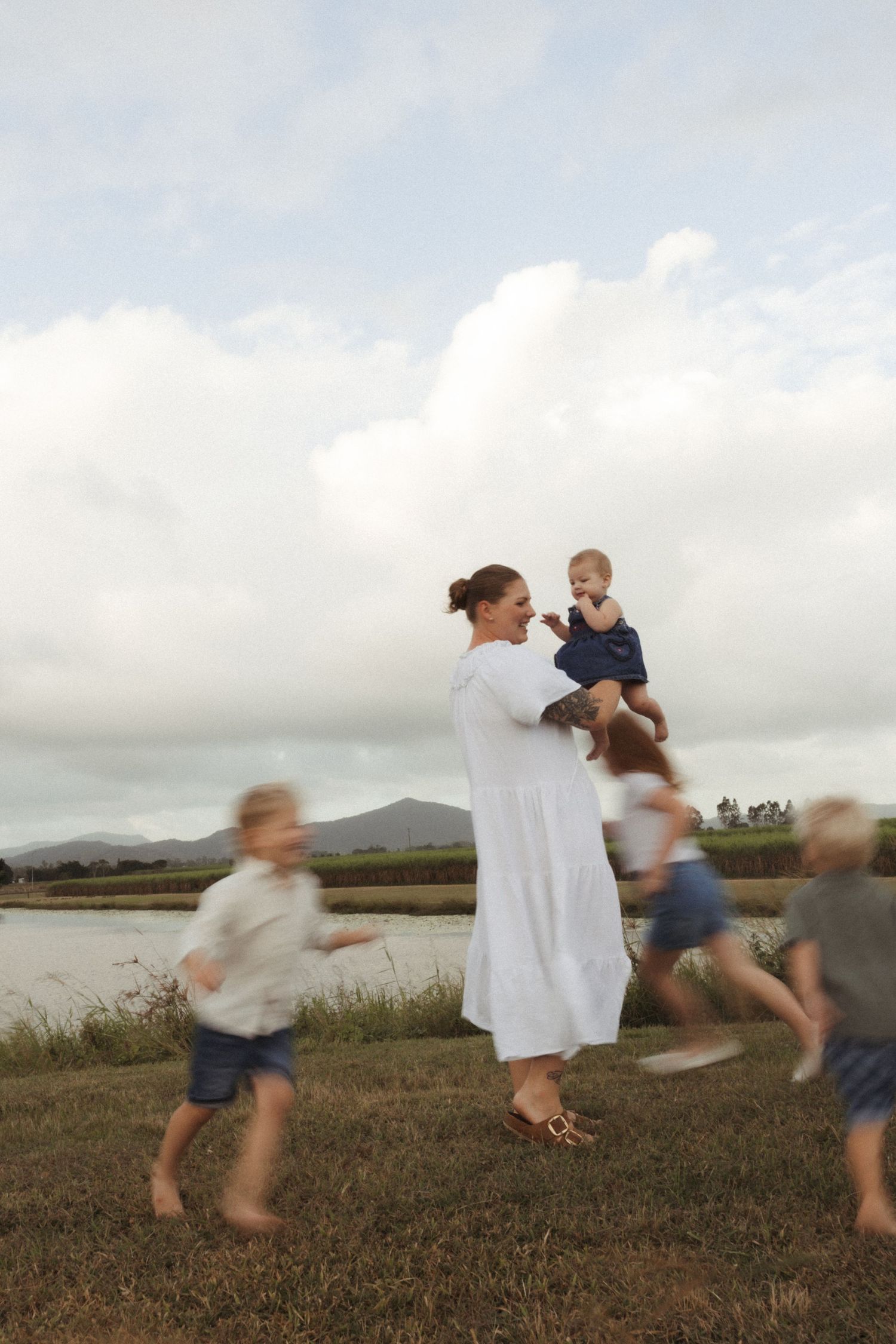 Playful outdoor scene with motion-blurred figures running around by the water.