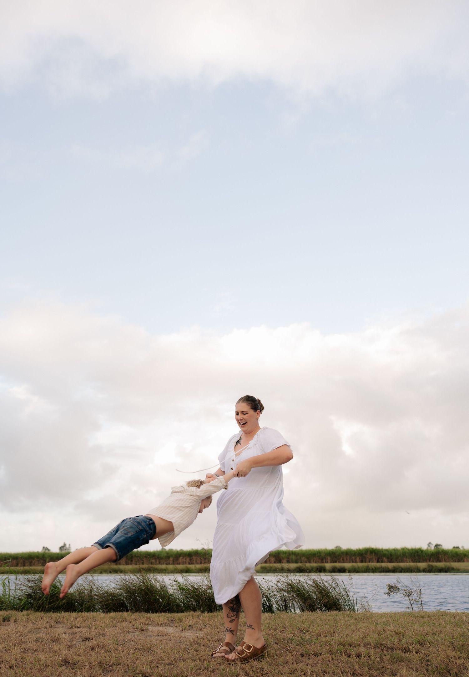 A playful swinging moment captured against a cloudy sky near water.