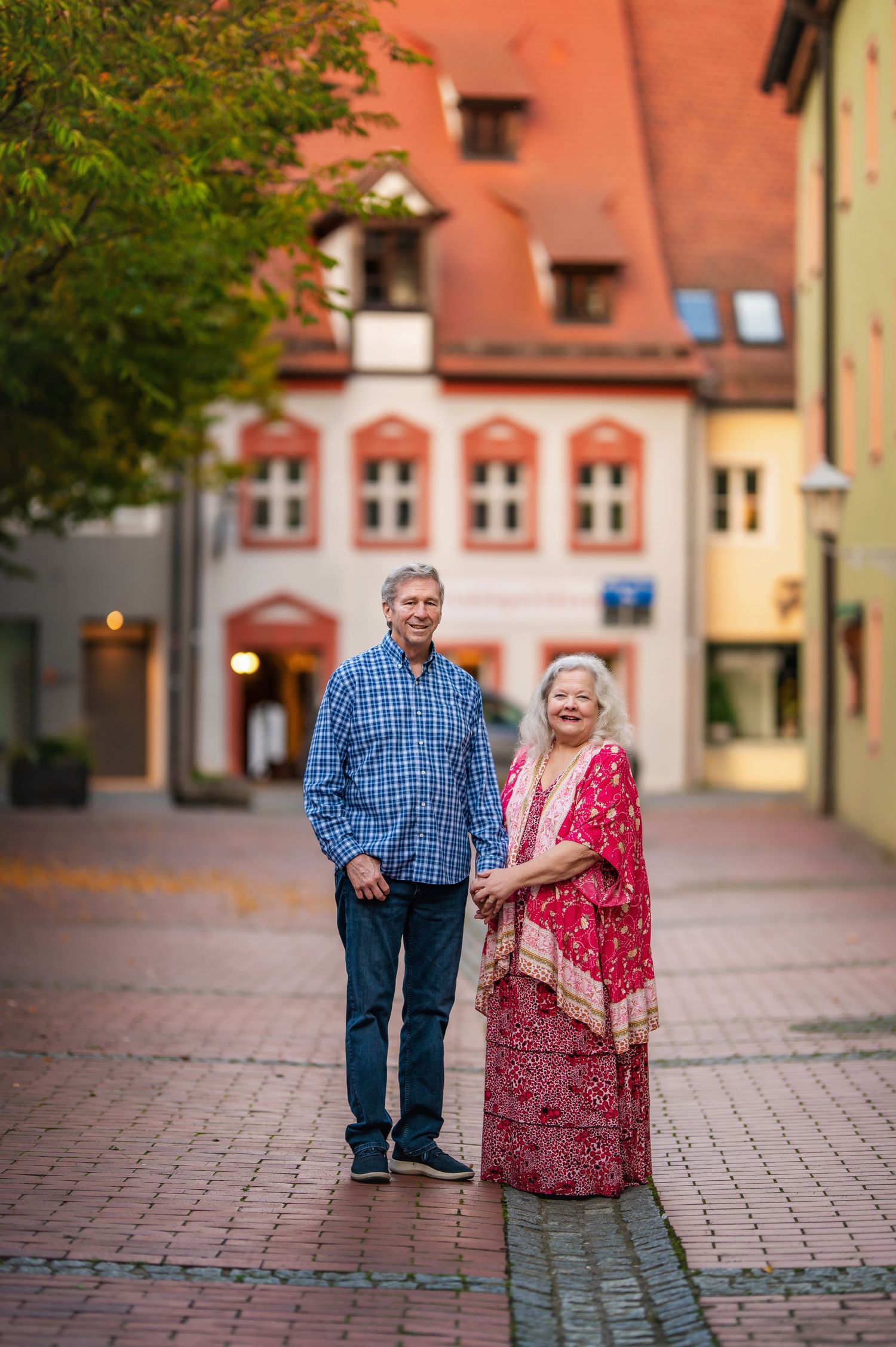 Couple poses together on cobblestone street surrounded by historic German architecture.