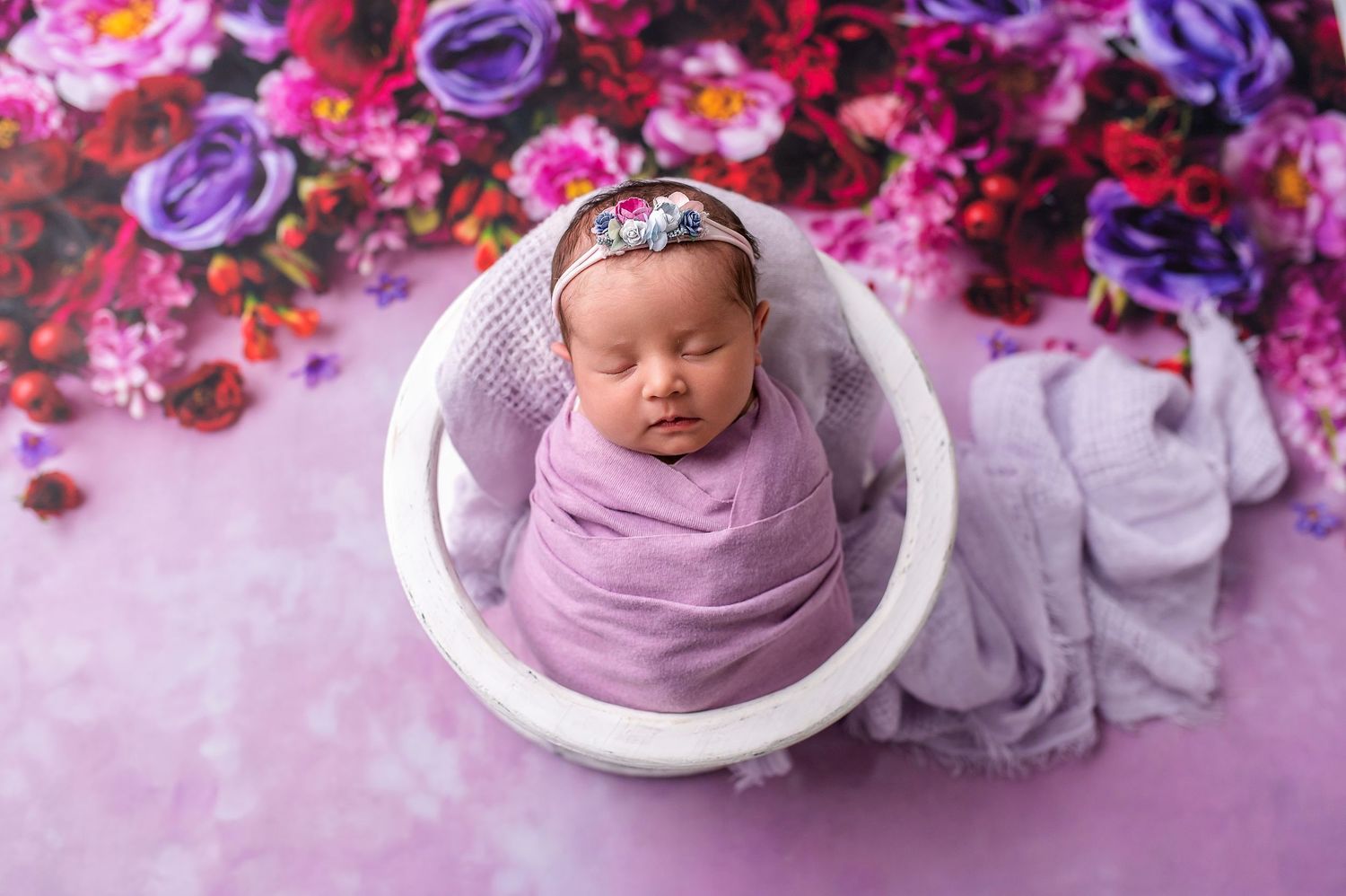 Newborn photography collage with purple and pink floral arrangements surrounding a small white bowl on soft fabric.