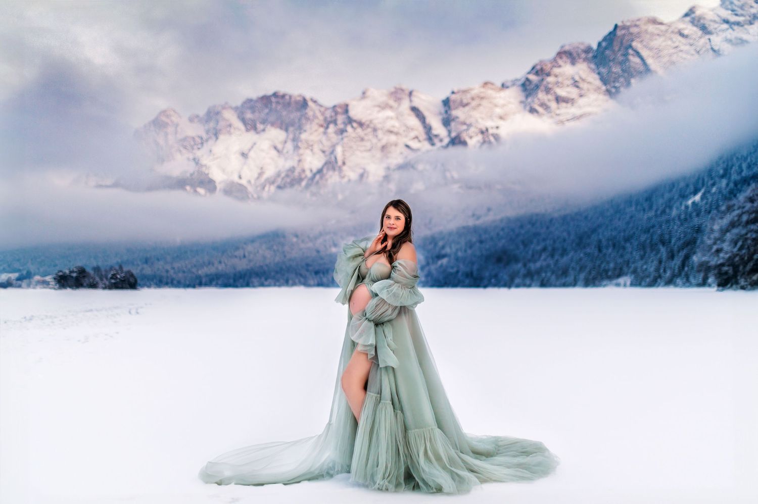 Figure in flowing mint green gown poses dramatically against snowy mountain landscape.