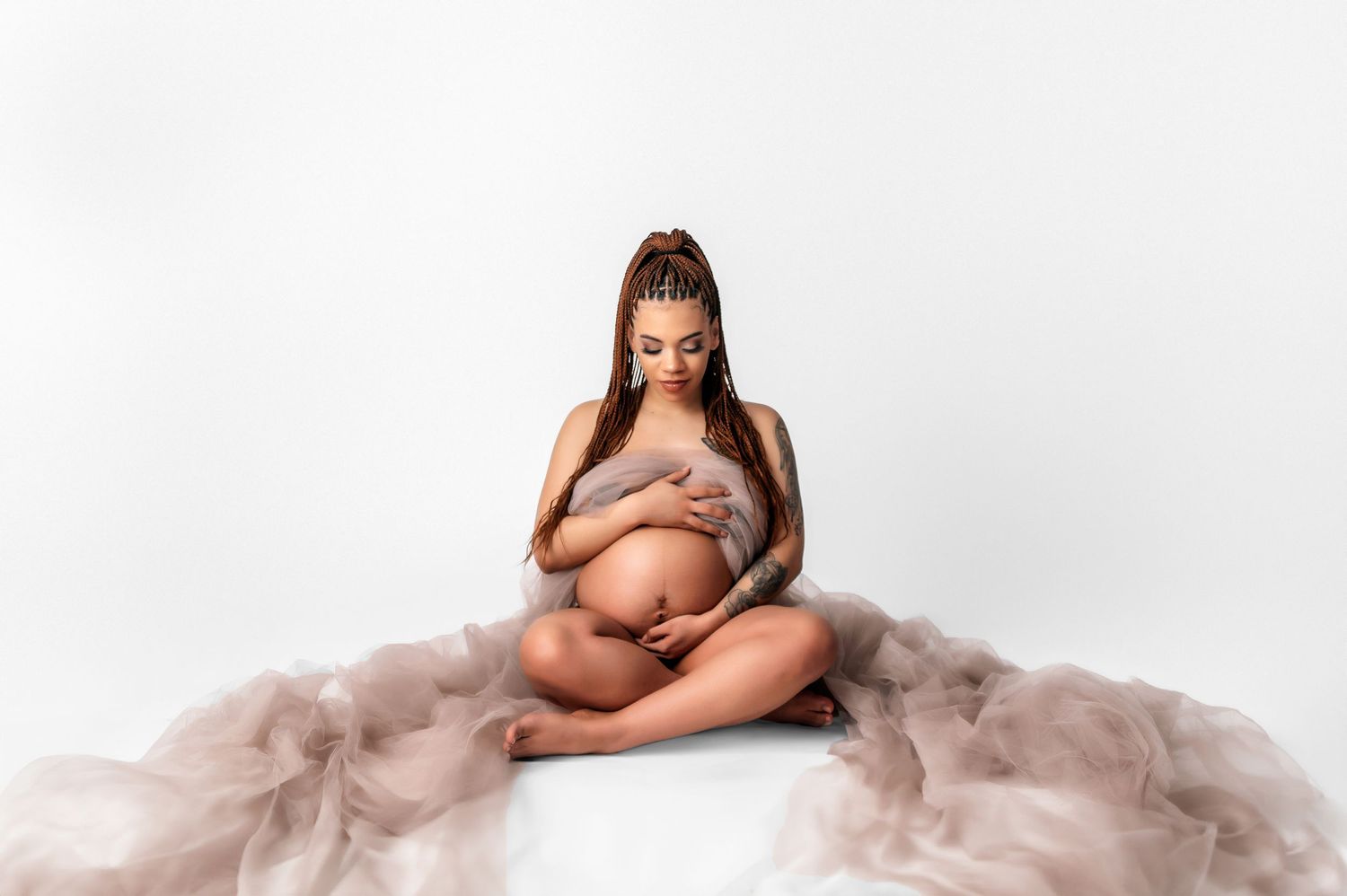 Artistic maternity boudoir session with flowing fabric in neutral tones.