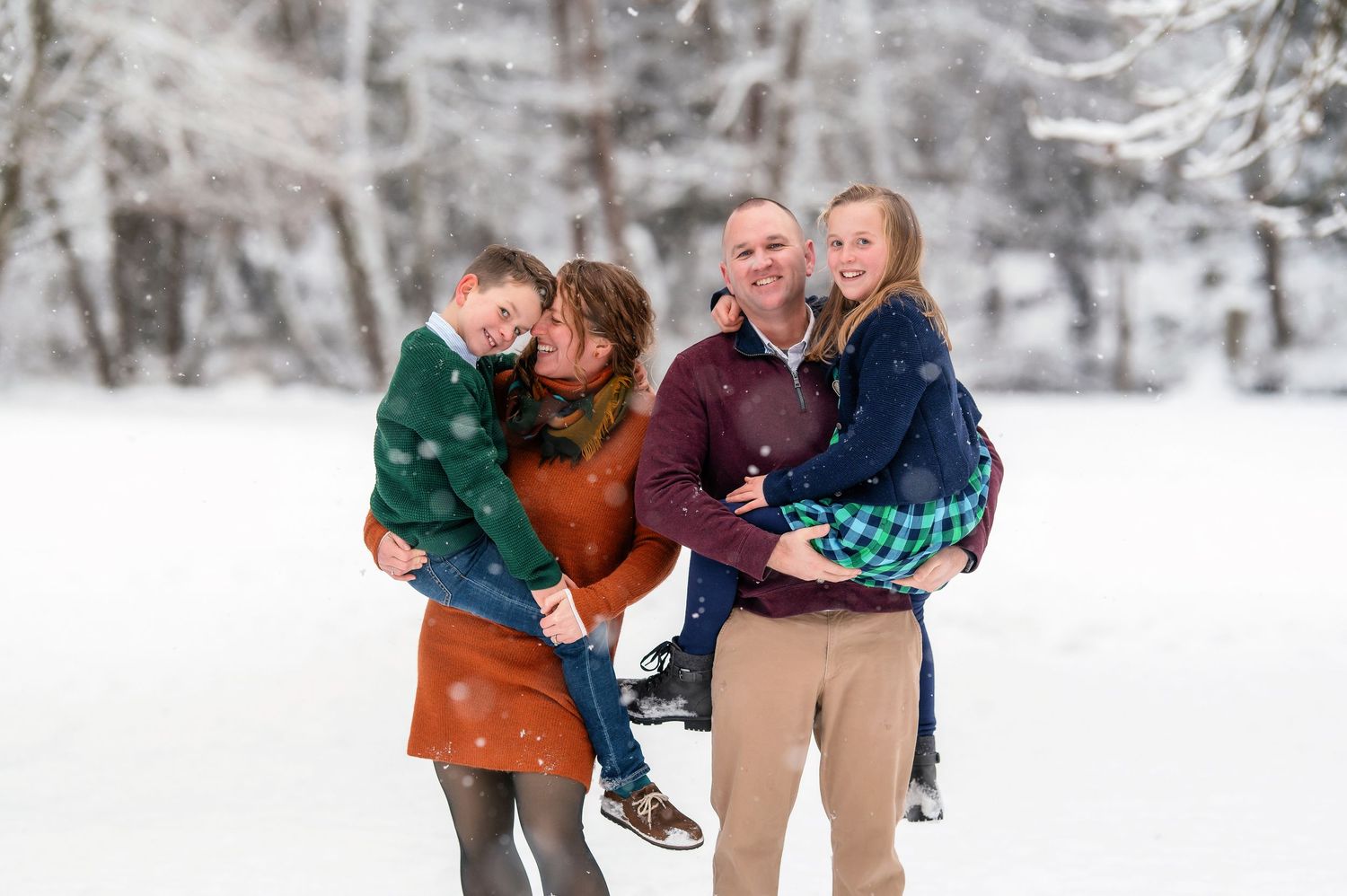 A winter family photoshoot in the snow with warm seasonal clothing.