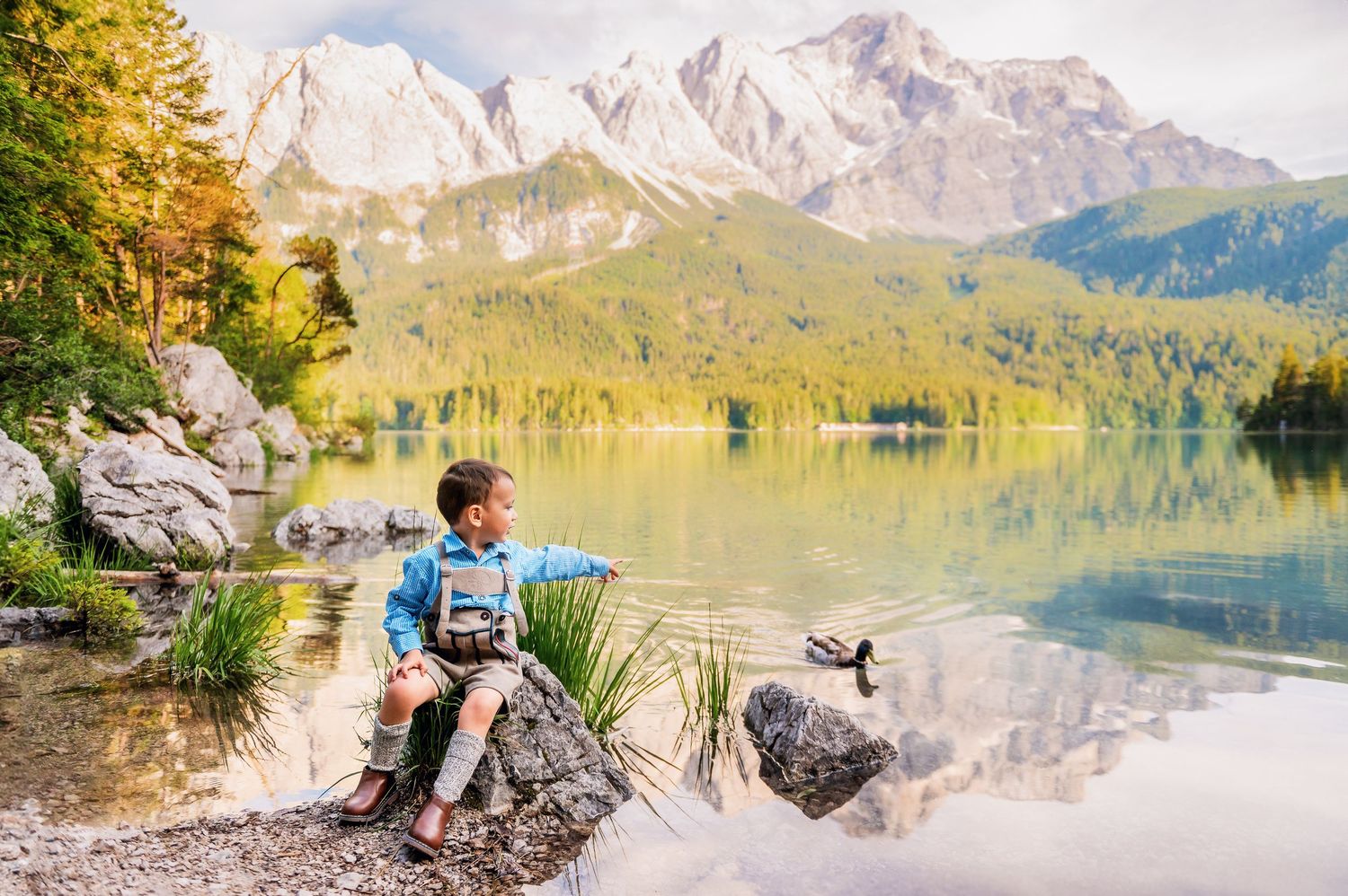 Panoramic mountain landscape with snow-capped peaks reflecting in a pristine alpine lake surrounded by wilderness.