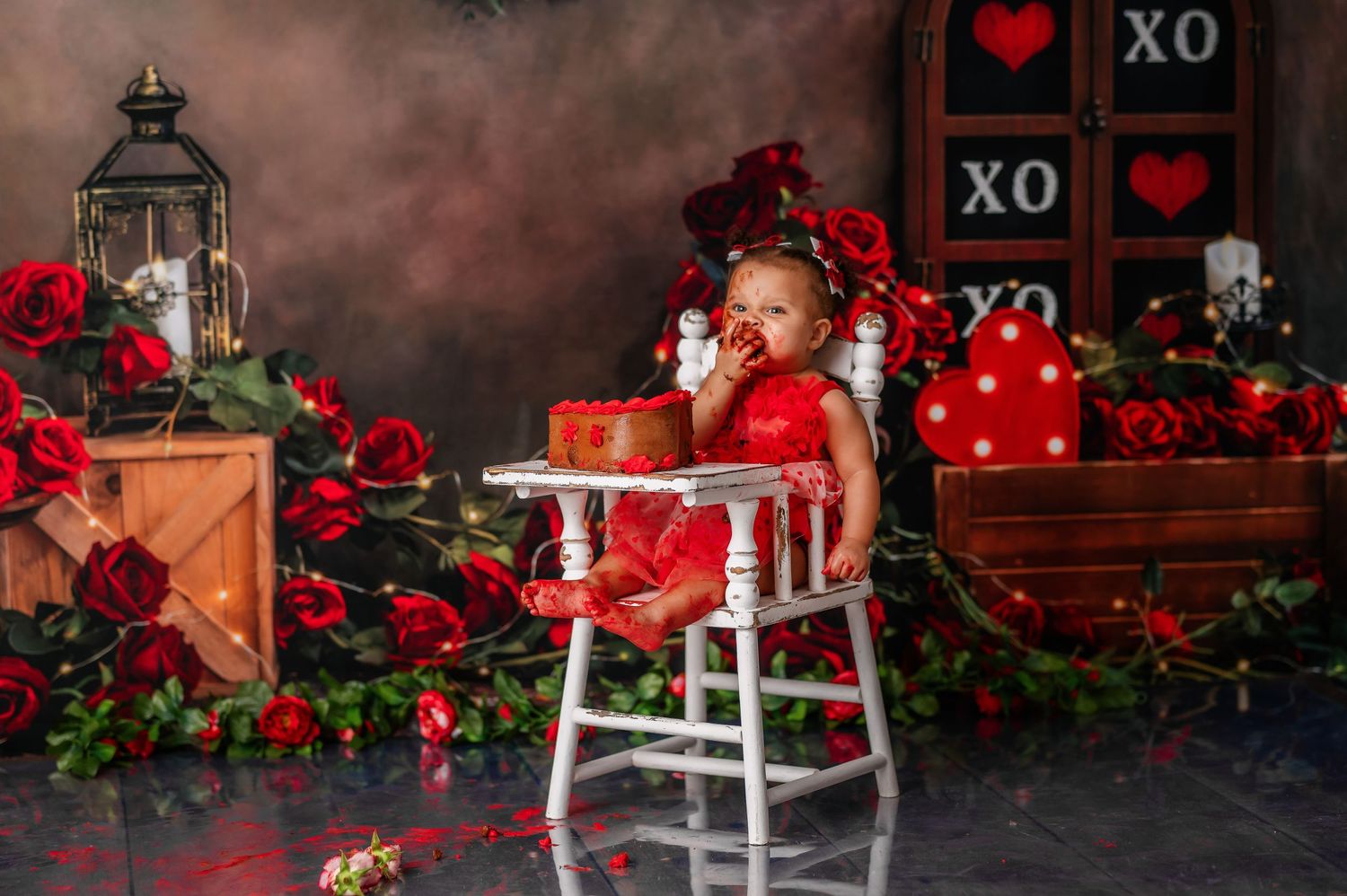 Valentine's day themed photo setup with red roses, lantern, and decorative hearts.
