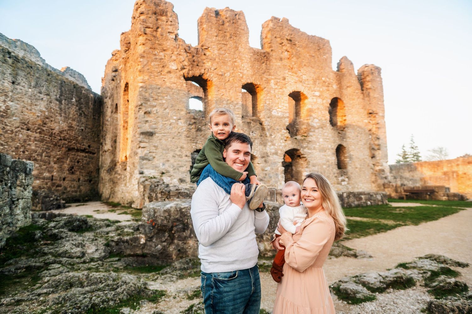 Historic castle ruins in warm sunlight provide a romantic backdrop for a couple's portrait.