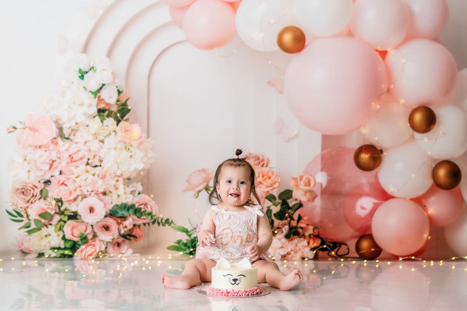Romantic pink balloon garland backdrop with copper accents and floral decorations.