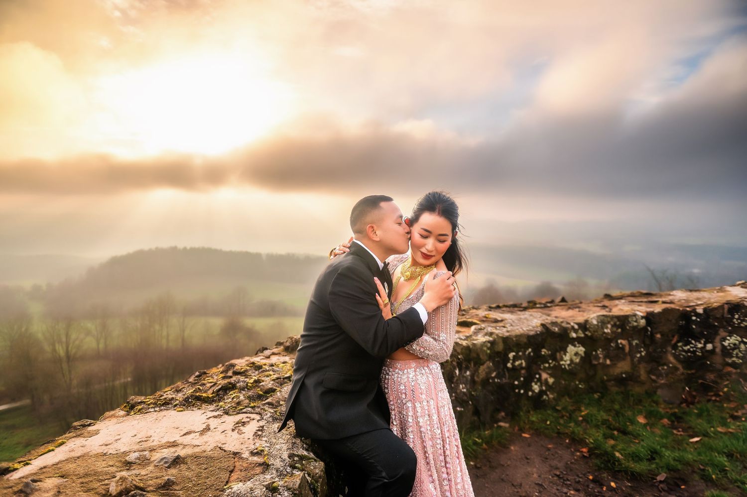 A tender embrace captured on a mountaintop during a golden sunset.