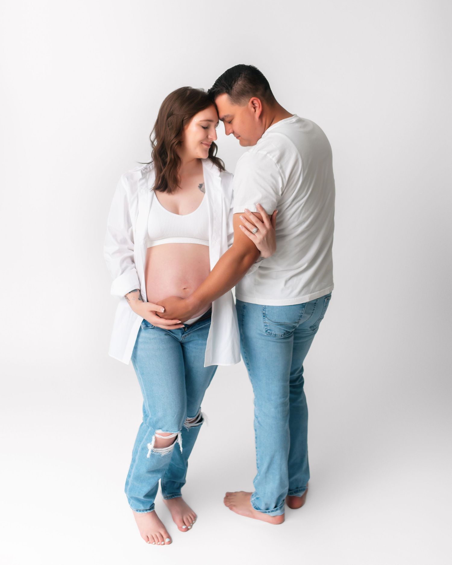 Intimate maternity portrait of couple in casual wear sharing gentle moment.