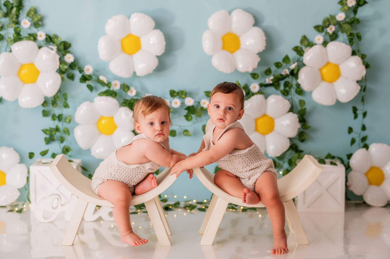 Spring themed photo setup with daisy backdrop and white benches for twin photography.