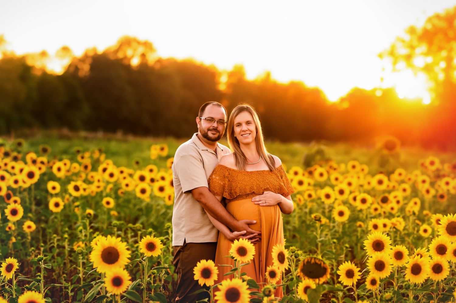 Maternity photoshoot in a vibrant sunflower field during golden hour.