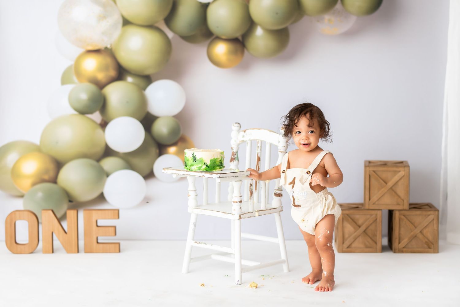First birthday photo setup with white chair and wooden letter blocks.