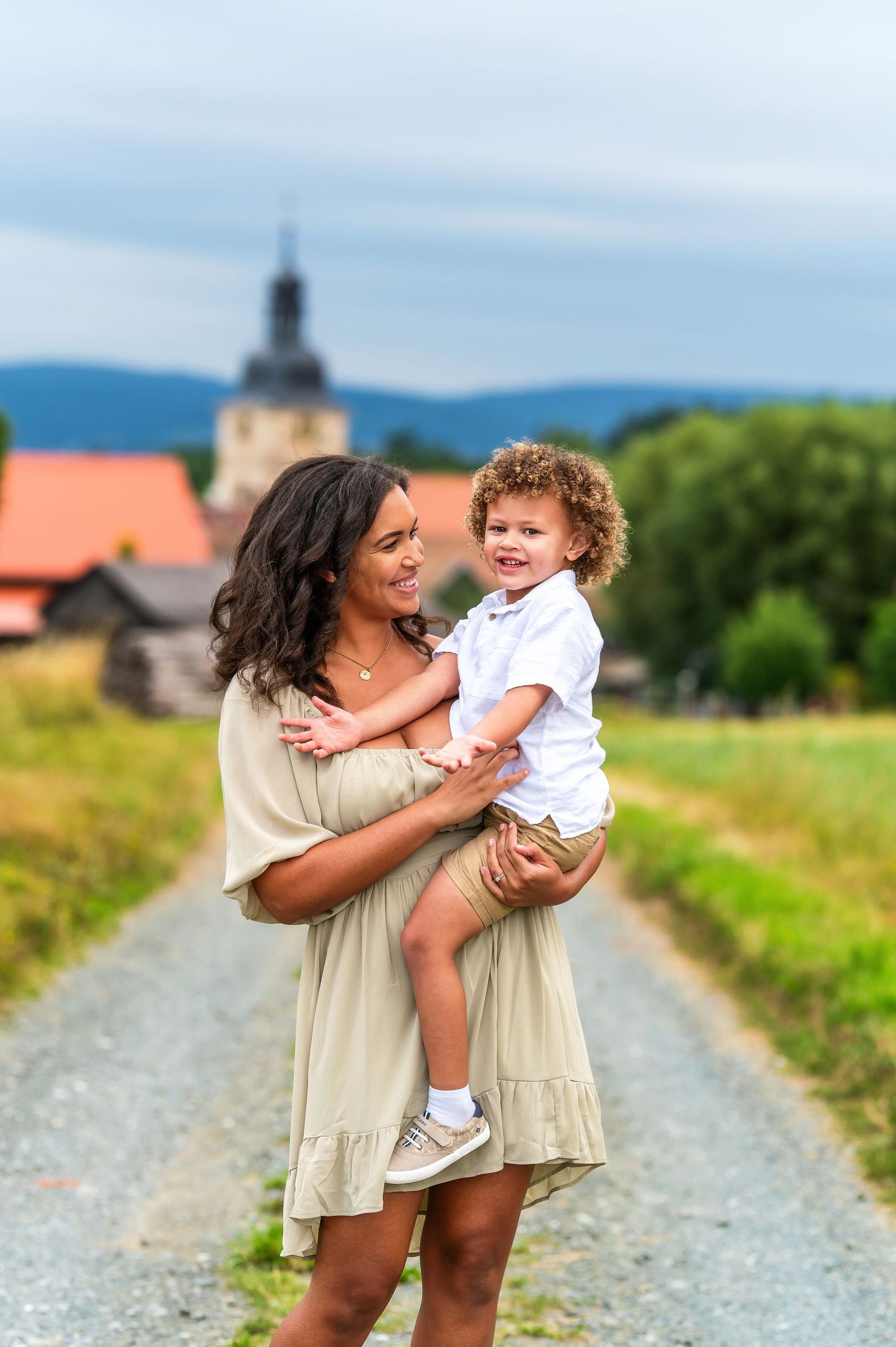 Family moment captured on a country path with mountains and church steeple in the background.