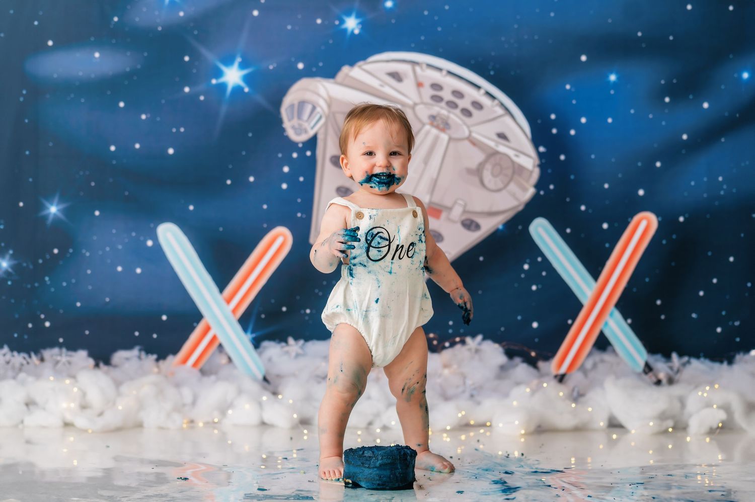 Space-themed cake smash photography setup with starry background and white cotton clouds.