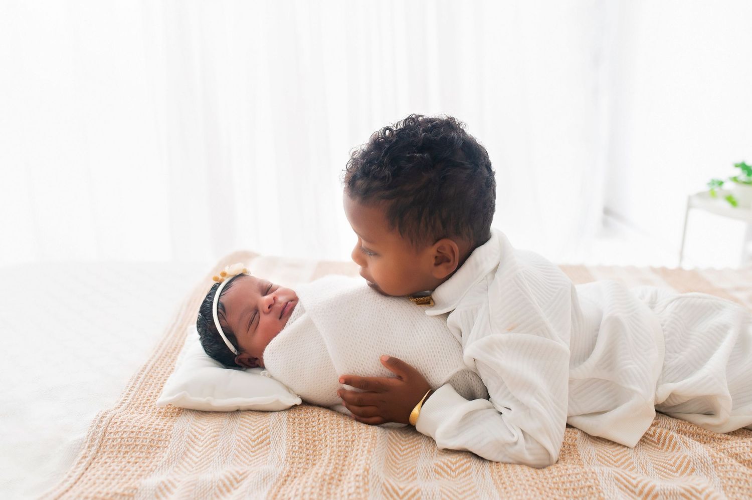 Minimalist newborn photo series with baby in white wrap on neutral backdrop.