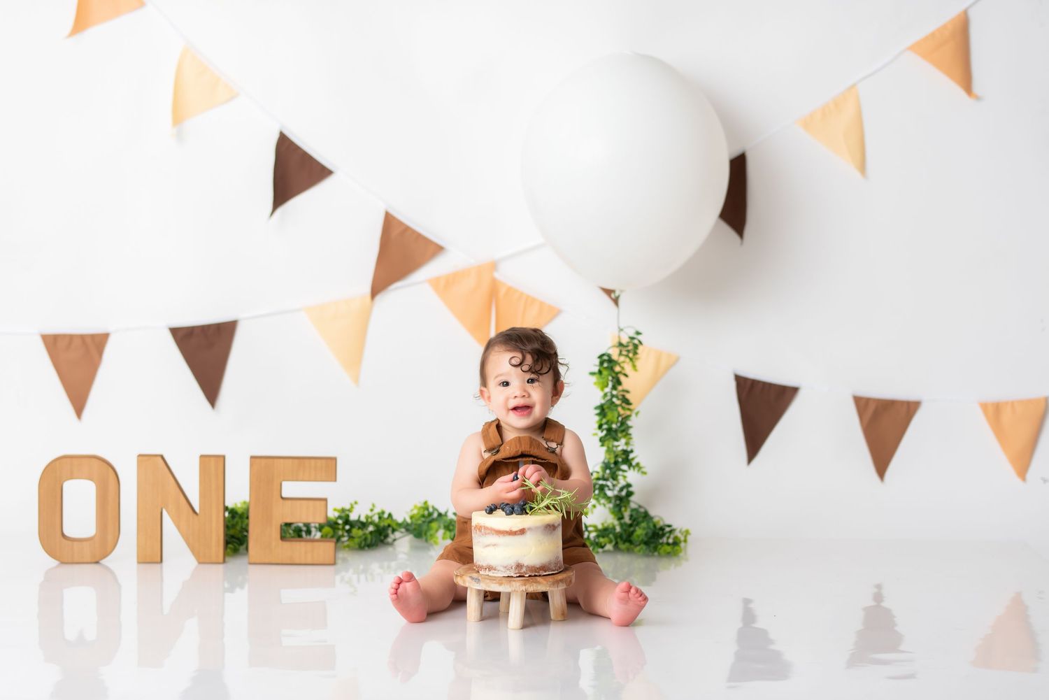 First birthday celebration setup with orange and brown triangle bunting and decorative wall display.