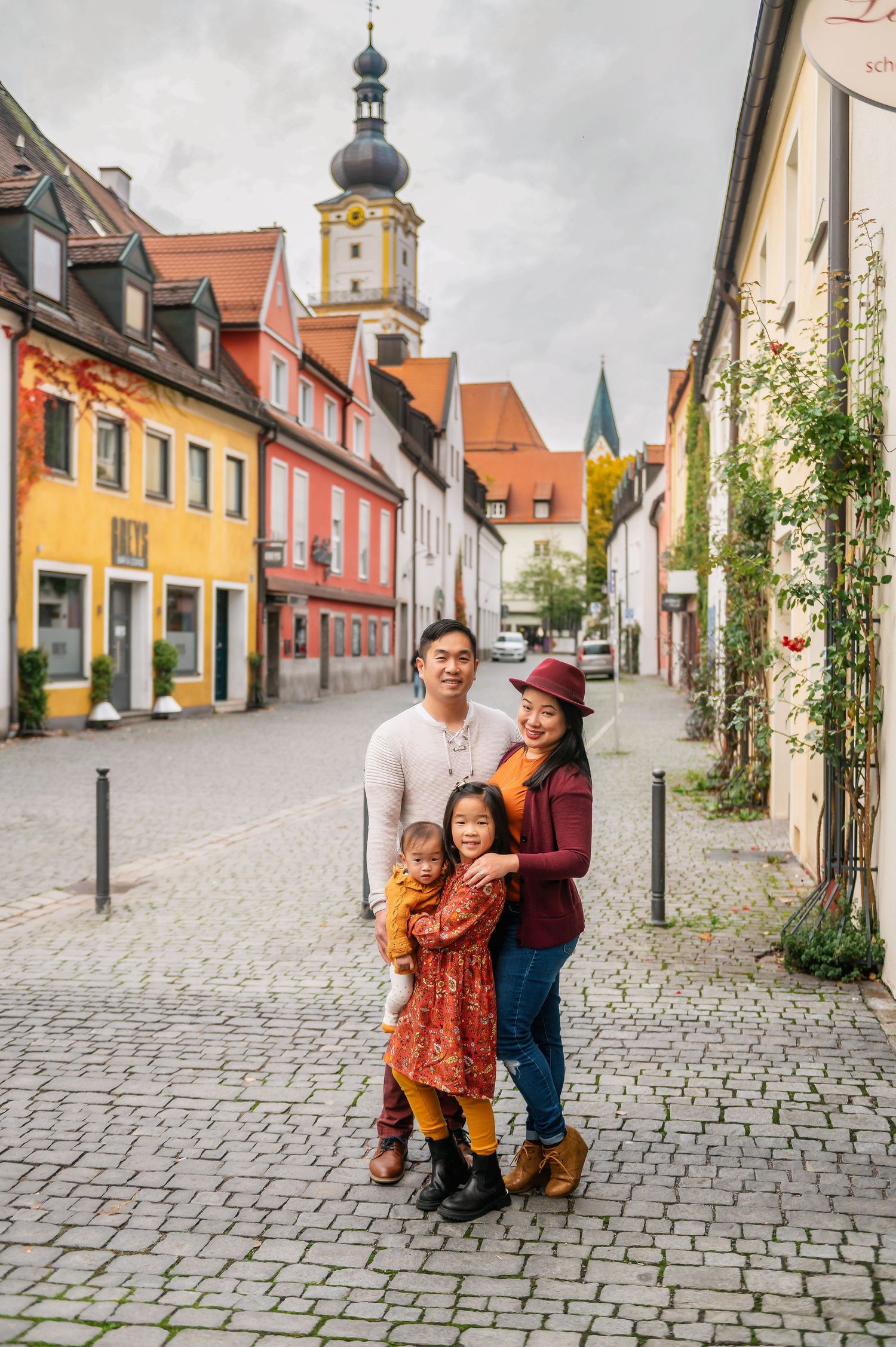 Charming European town street with colorful buildings and historic clock tower in background.