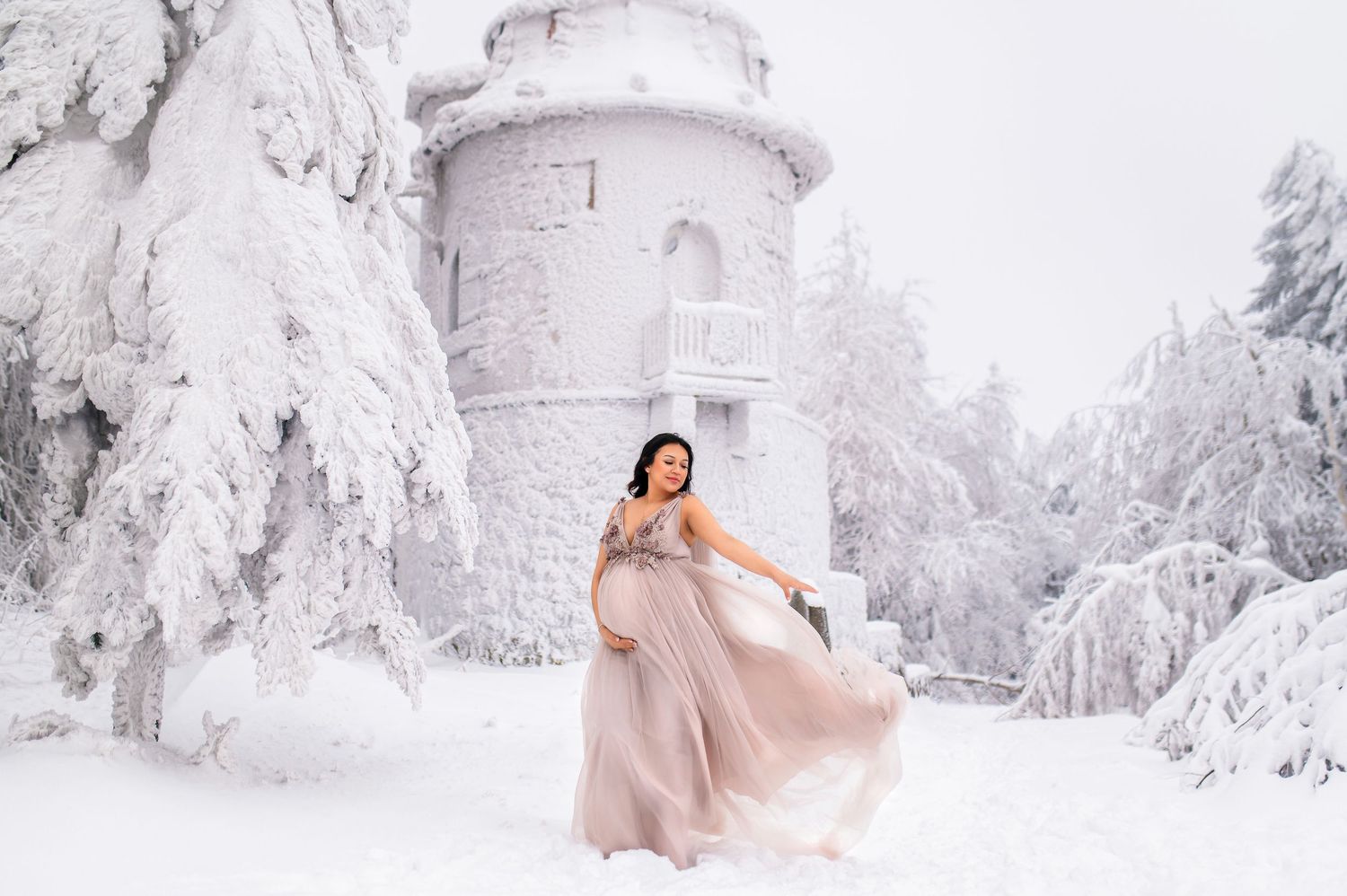 A figure in a flowing pink dress dances gracefully in a serene winter wonderland setting with snow-covered trees.