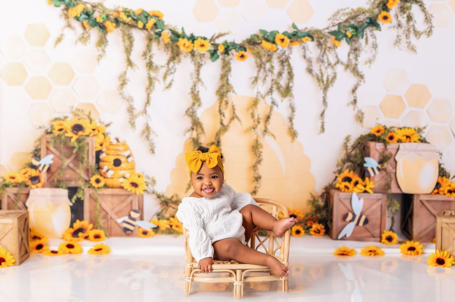 Baby cake smash session with sunflower decorations and hanging greenery garlands.