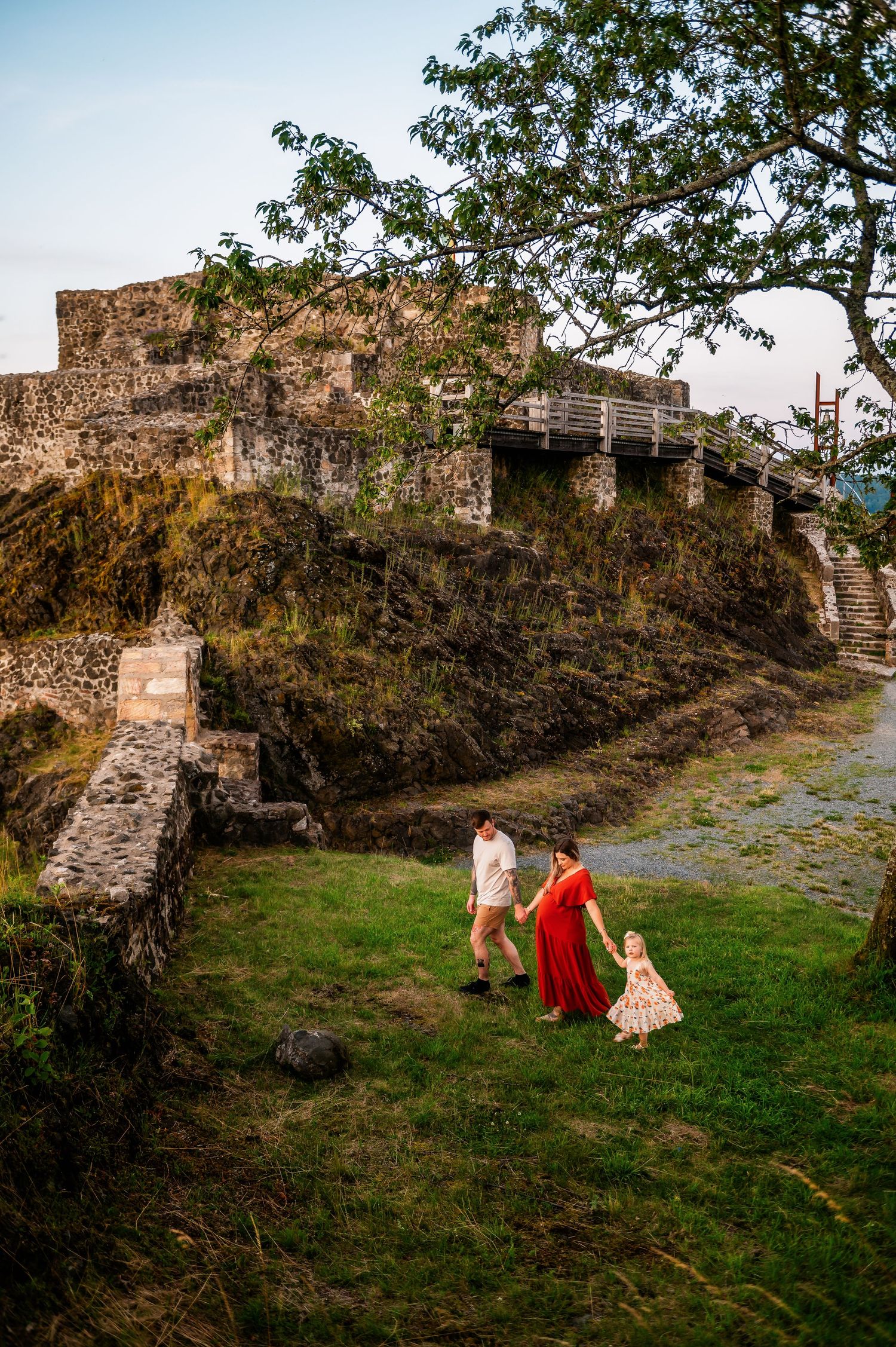 Family walks near historic stone castle ruins during outdoor photo session.