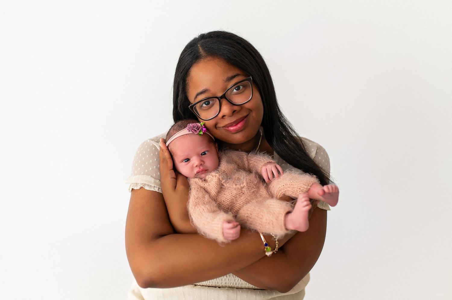 Mother holding newborn baby in tender portrait against white background.