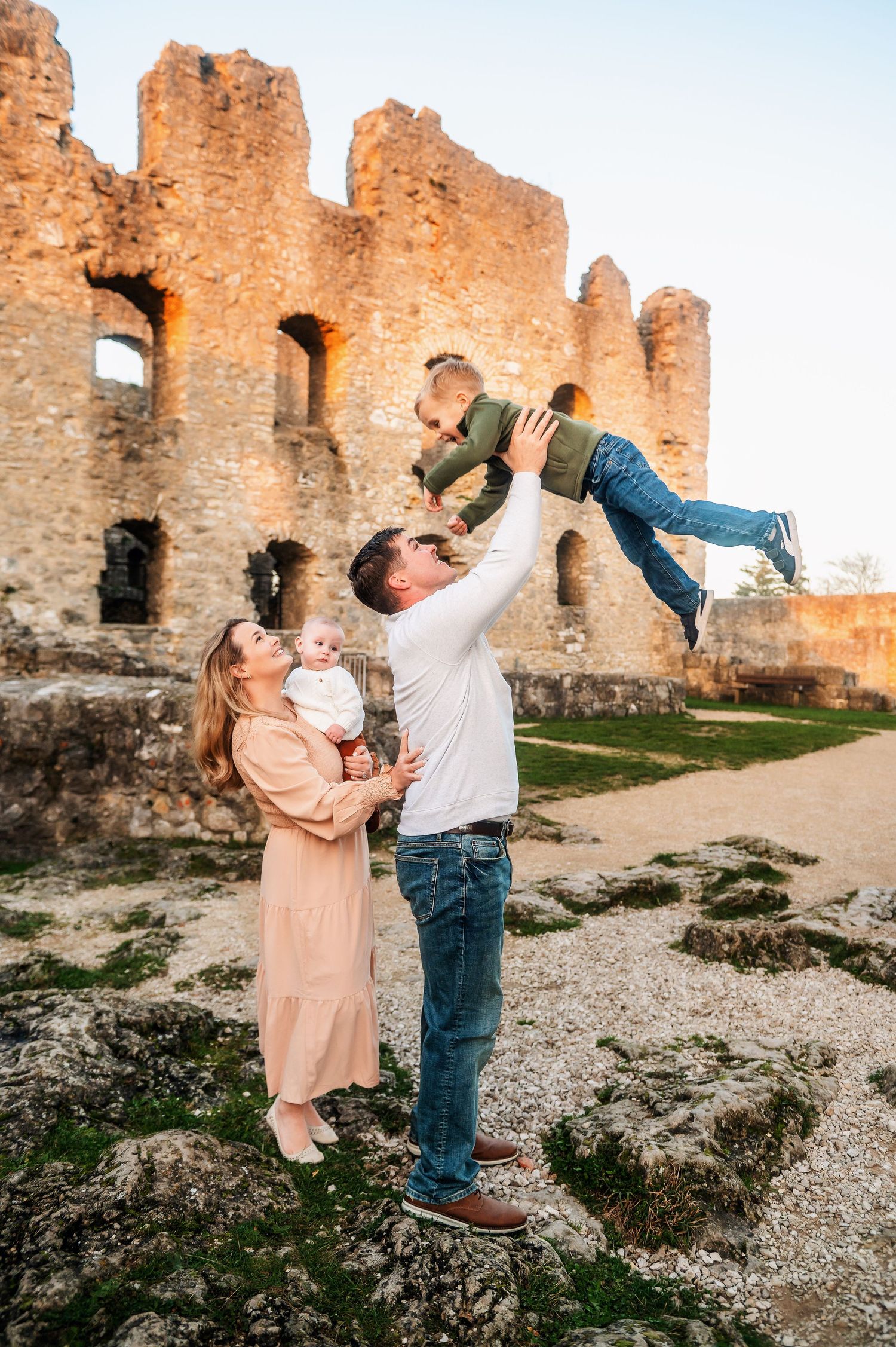 Family playing and having fun in front of weathered castle ruins on a sunny day.