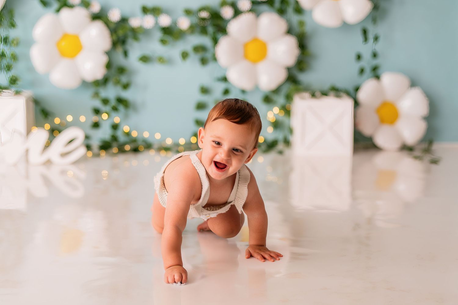Baby photography scene with daisy wall decorations and white blocks.