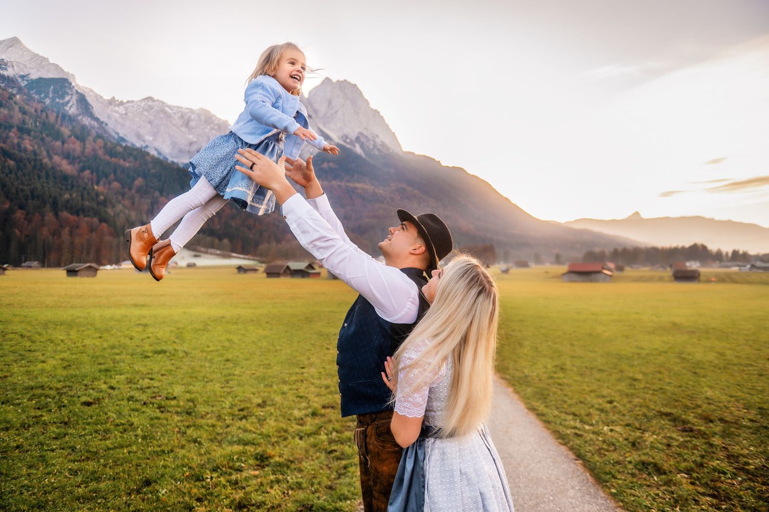 Couple sharing a joyful embrace while dancing in a scenic mountain meadow at sunset.