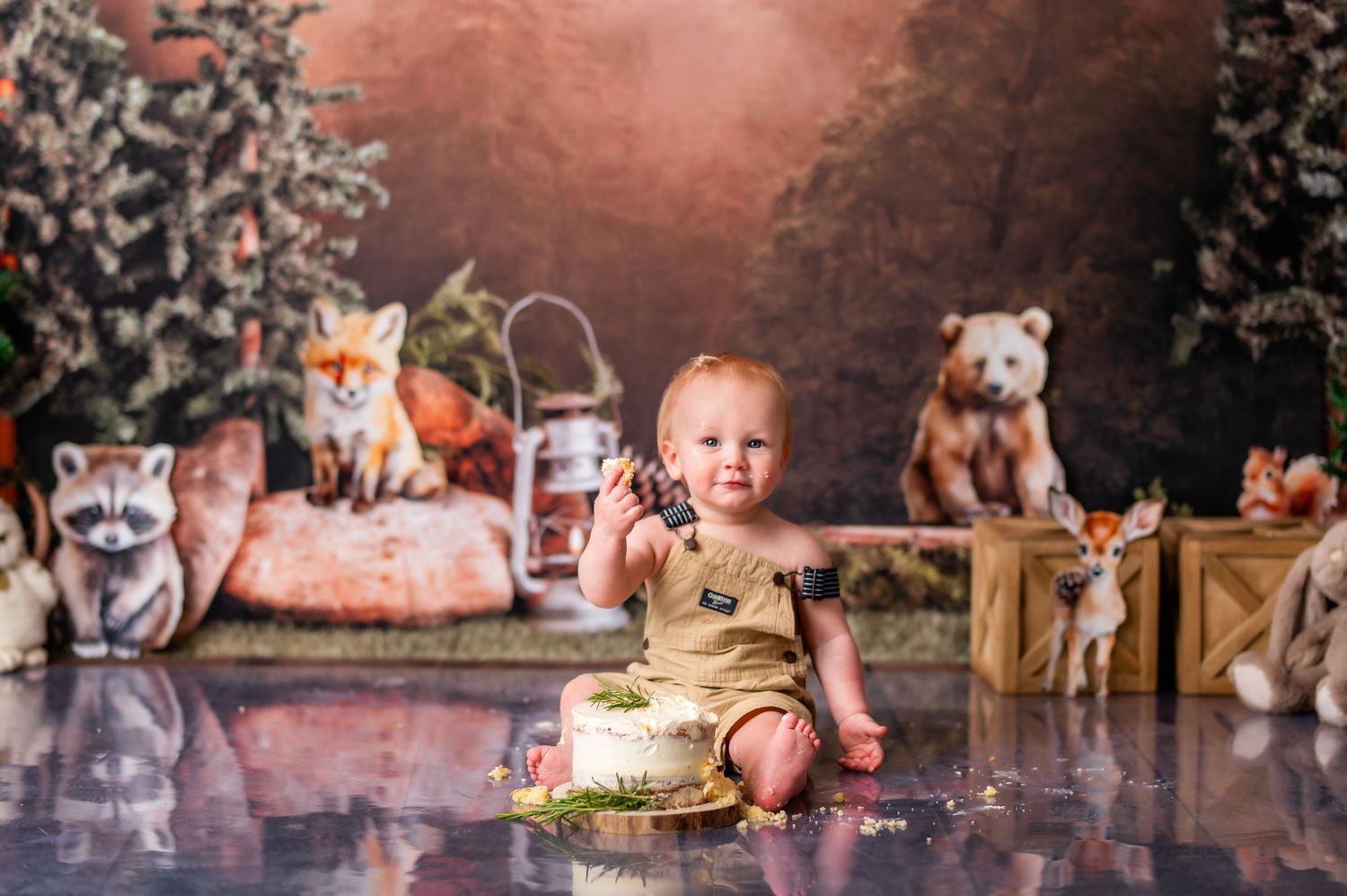 Woodland themed cake smash setup with fox decorations and rustic backdrop.