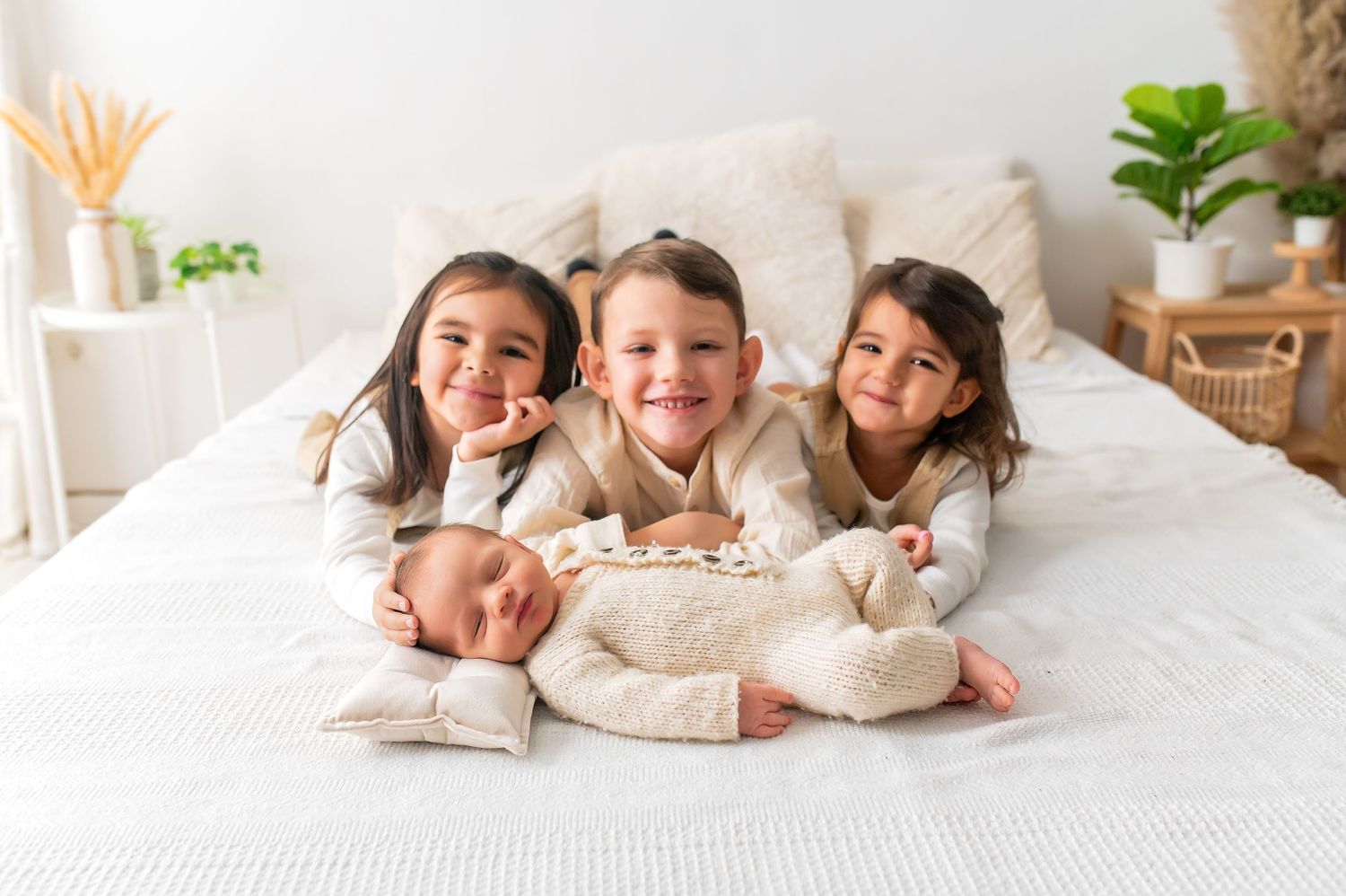 Happy family members gathered together on white bed with baby.