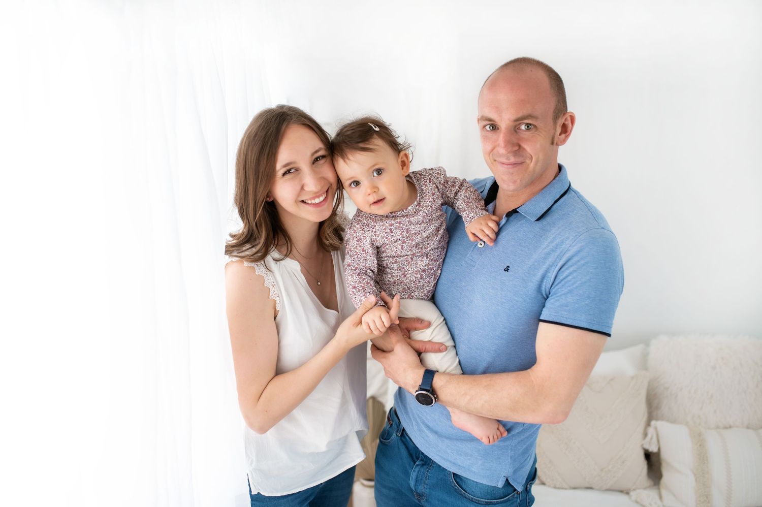 Family portrait in bright studio wearing coordinated blue and white casual outfits.