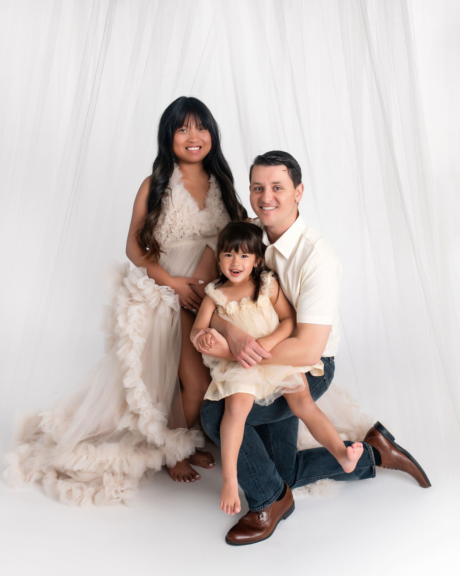 Family photoshoot in a studio with white backdrop showing playful and intimate moments between parent and child.