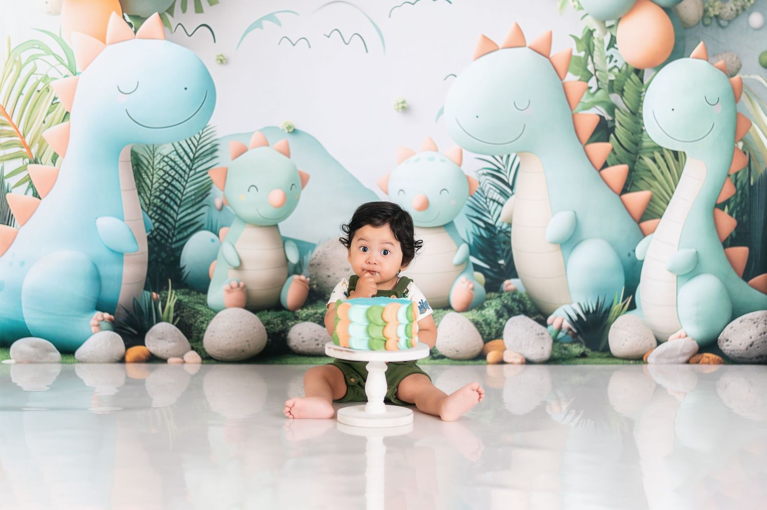 Dinosaur themed birthday setup with large blue balloon decorations and tropical leaves.
