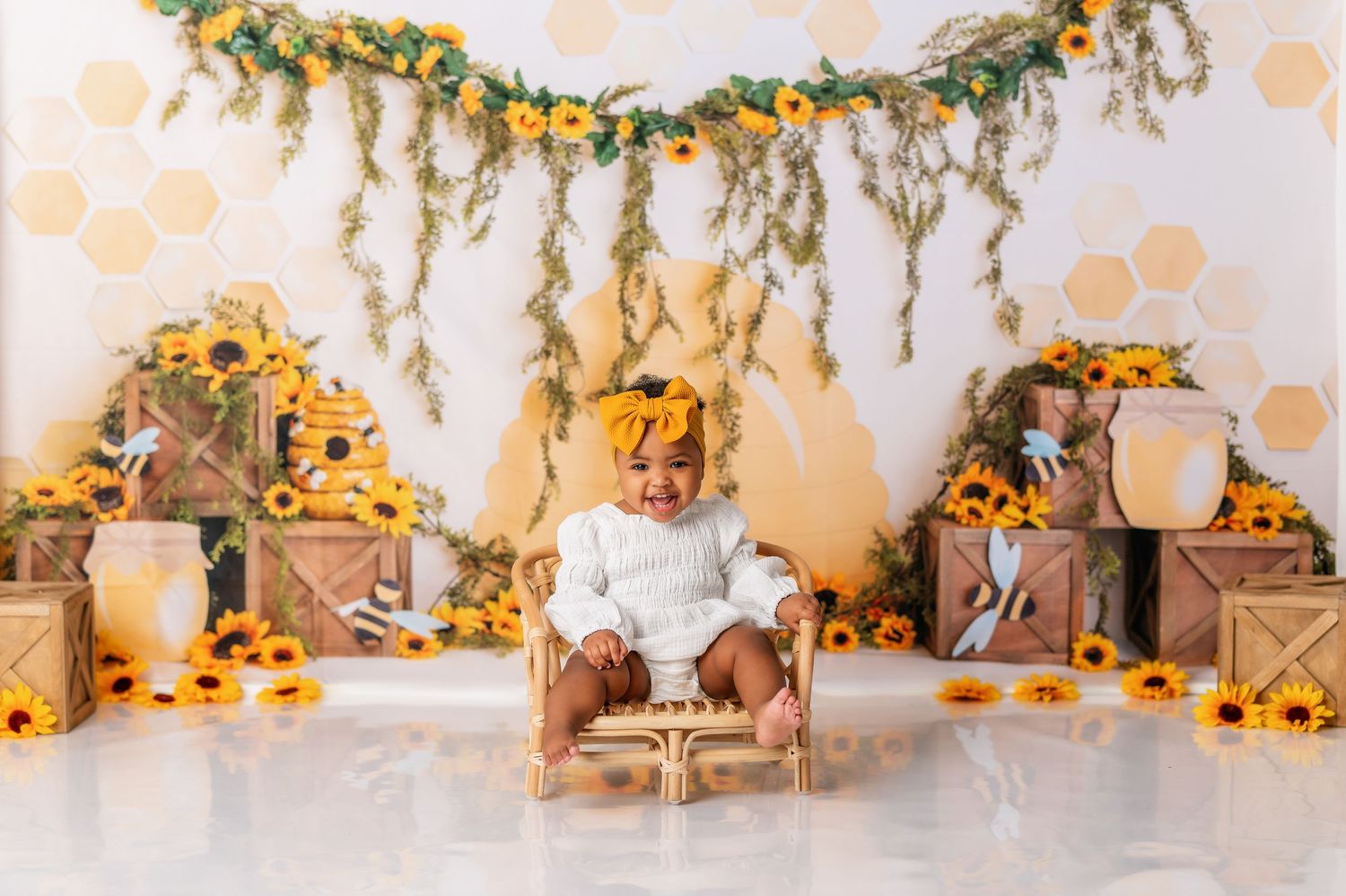 Sunflower themed first birthday setup with hanging greenery and rustic decorations.
