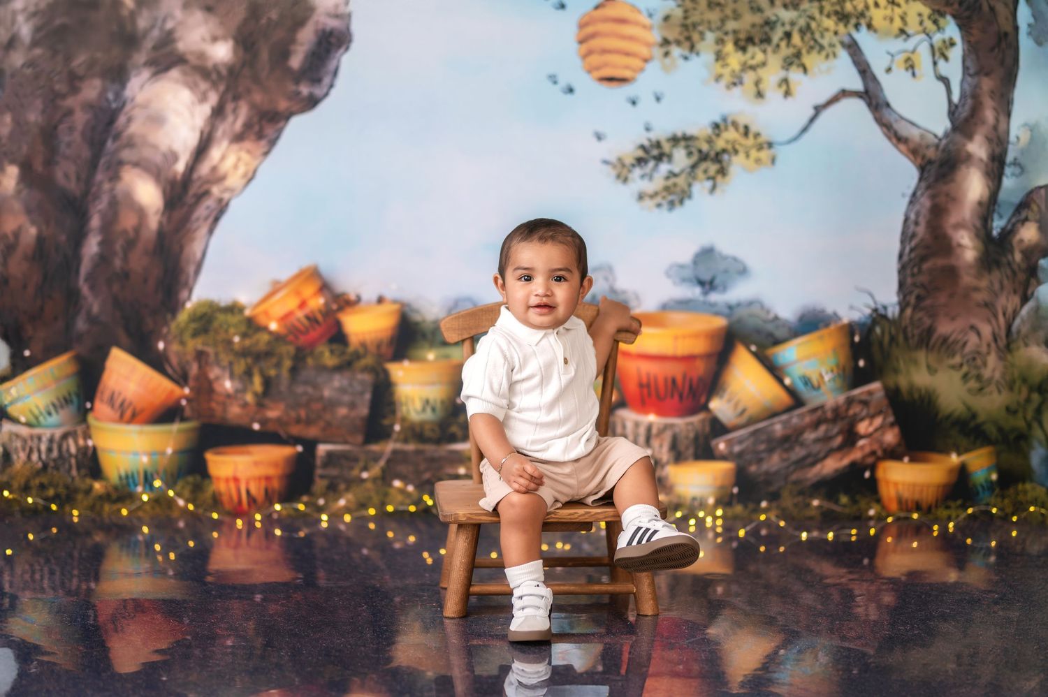 Whimsical outdoor honey pot themed photo setup with twinkling lights and rustic backdrop.