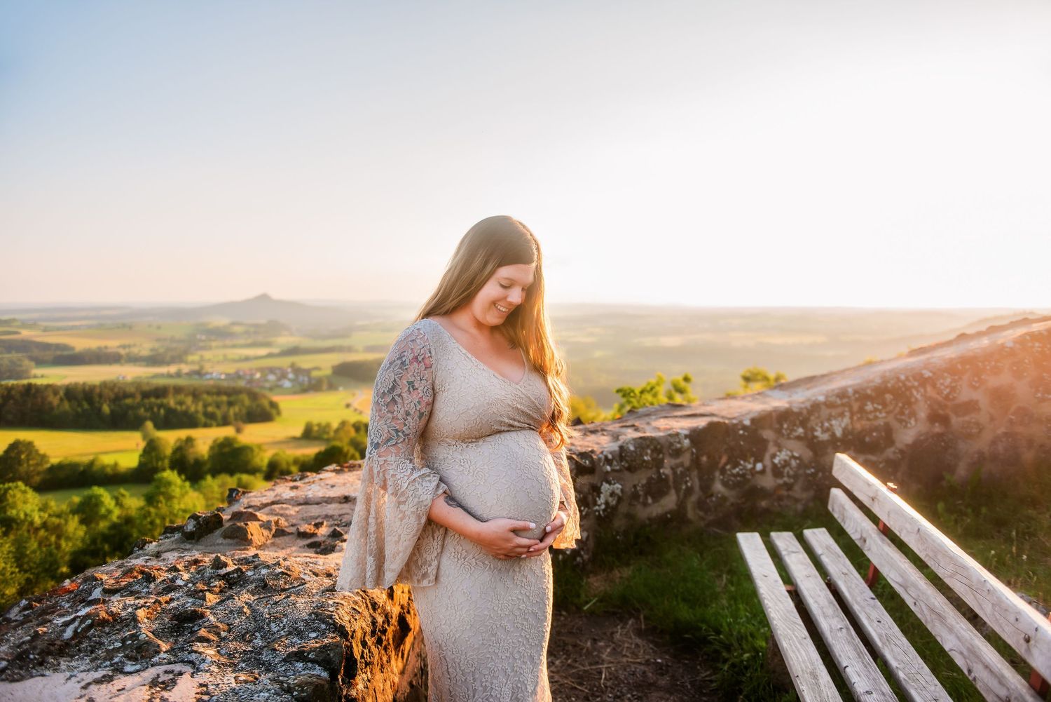 Scenic hilltop maternity session at sunset with panoramic countryside views.